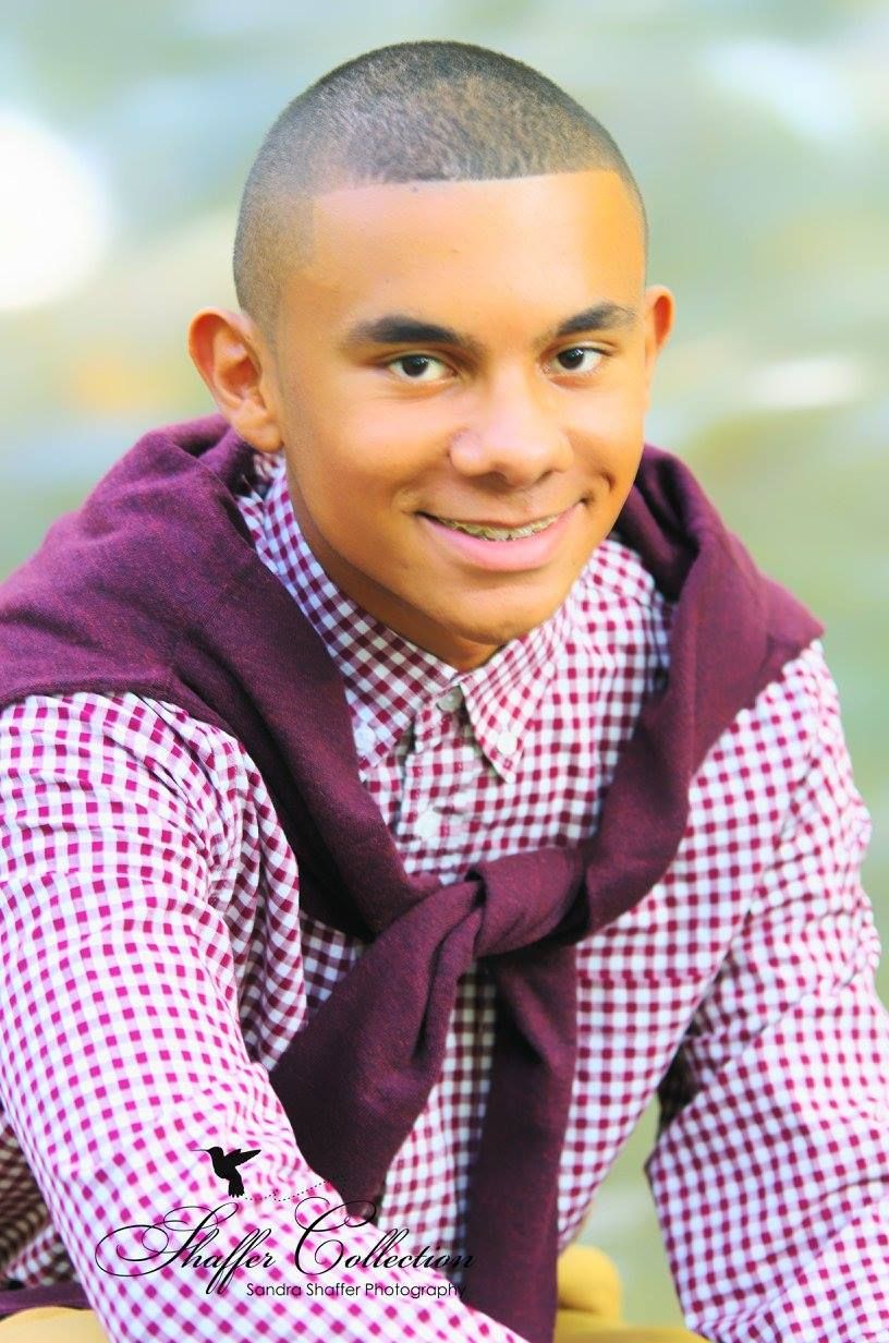 Portrait with burgundy hoodie and checkered shirt against soft blurred background.