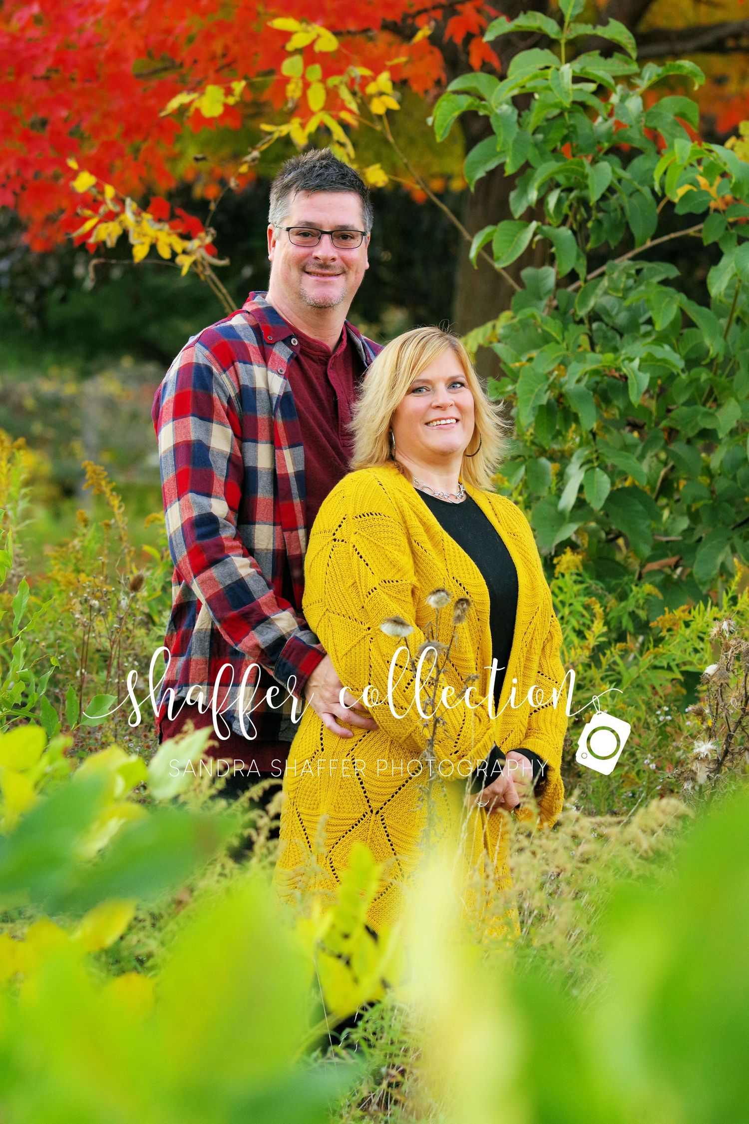 An outdoor portrait with vibrant autumn colors and foliage in the background.