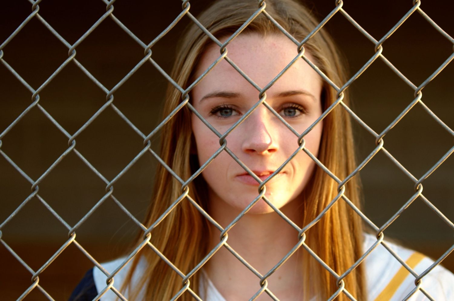 Portrait through chain link fence creating dramatic pattern effect.