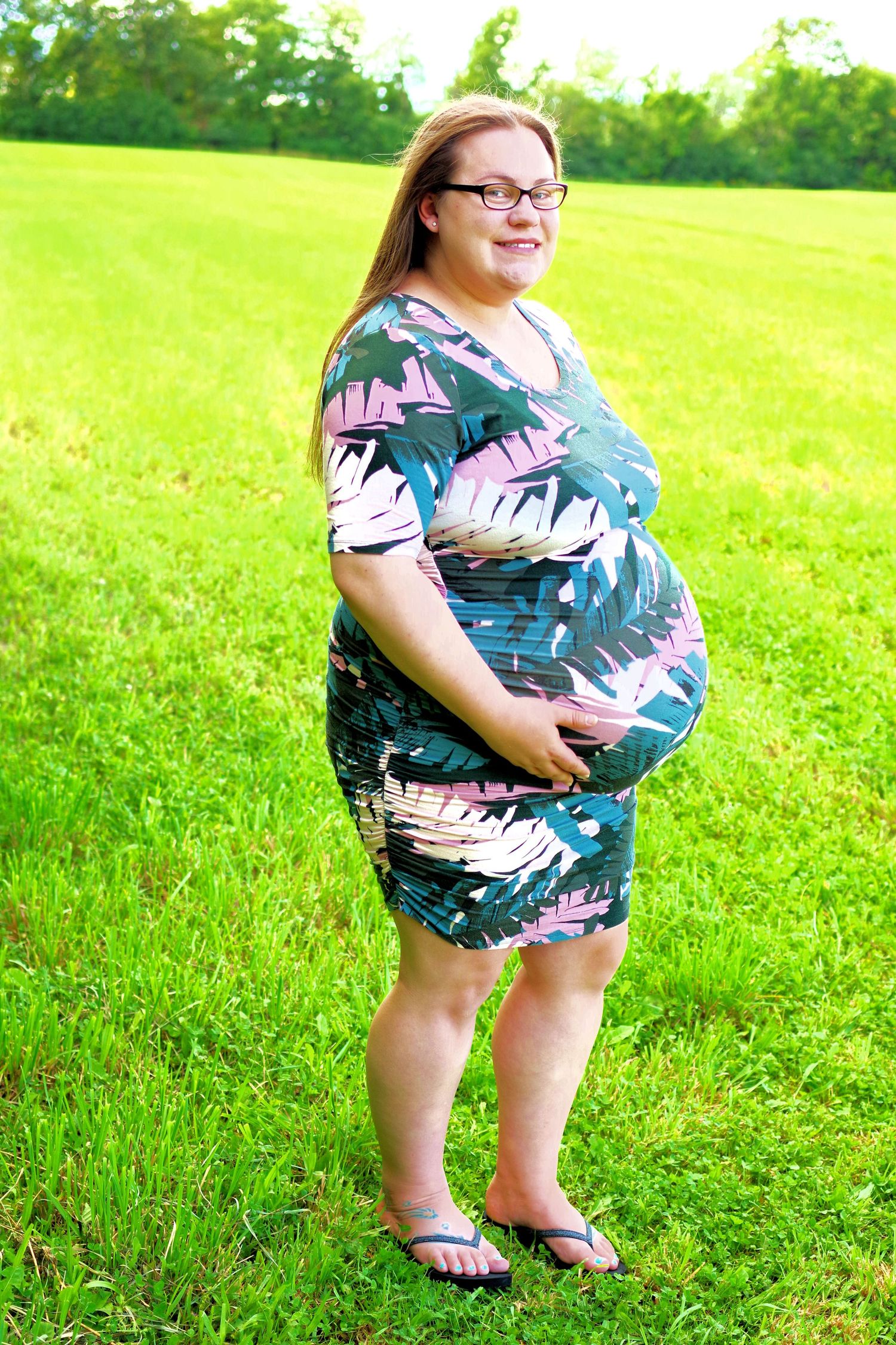 A tropical print romper outfit photographed in a sunny green field.