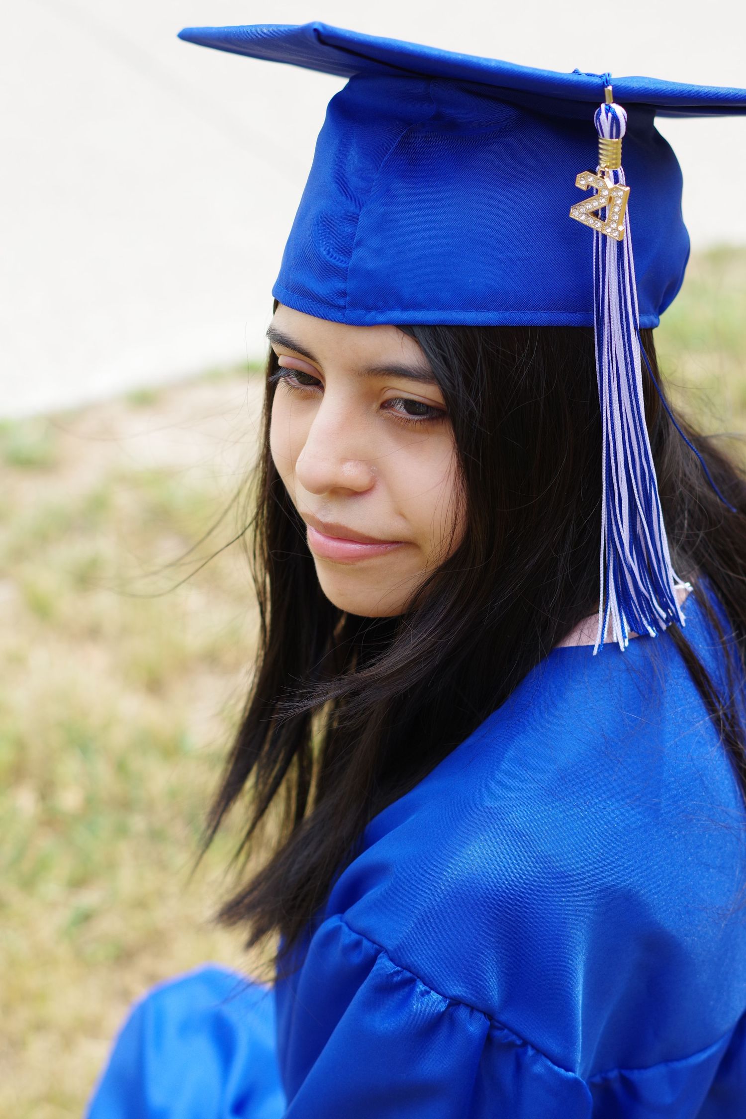 Profile view of graduate in traditional blue graduation attire with tassel.