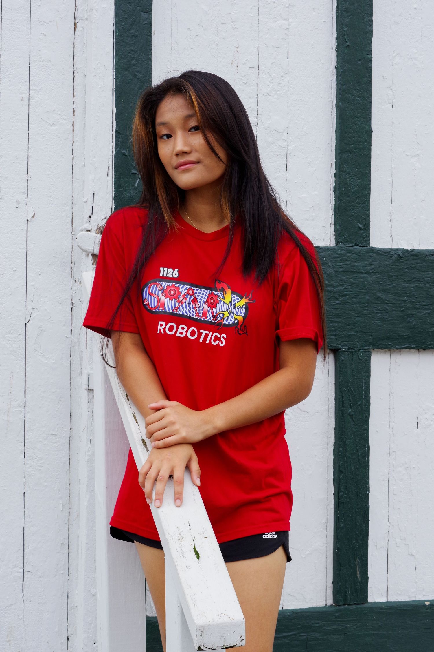 Portrait against white wall wearing red robotics team shirt.