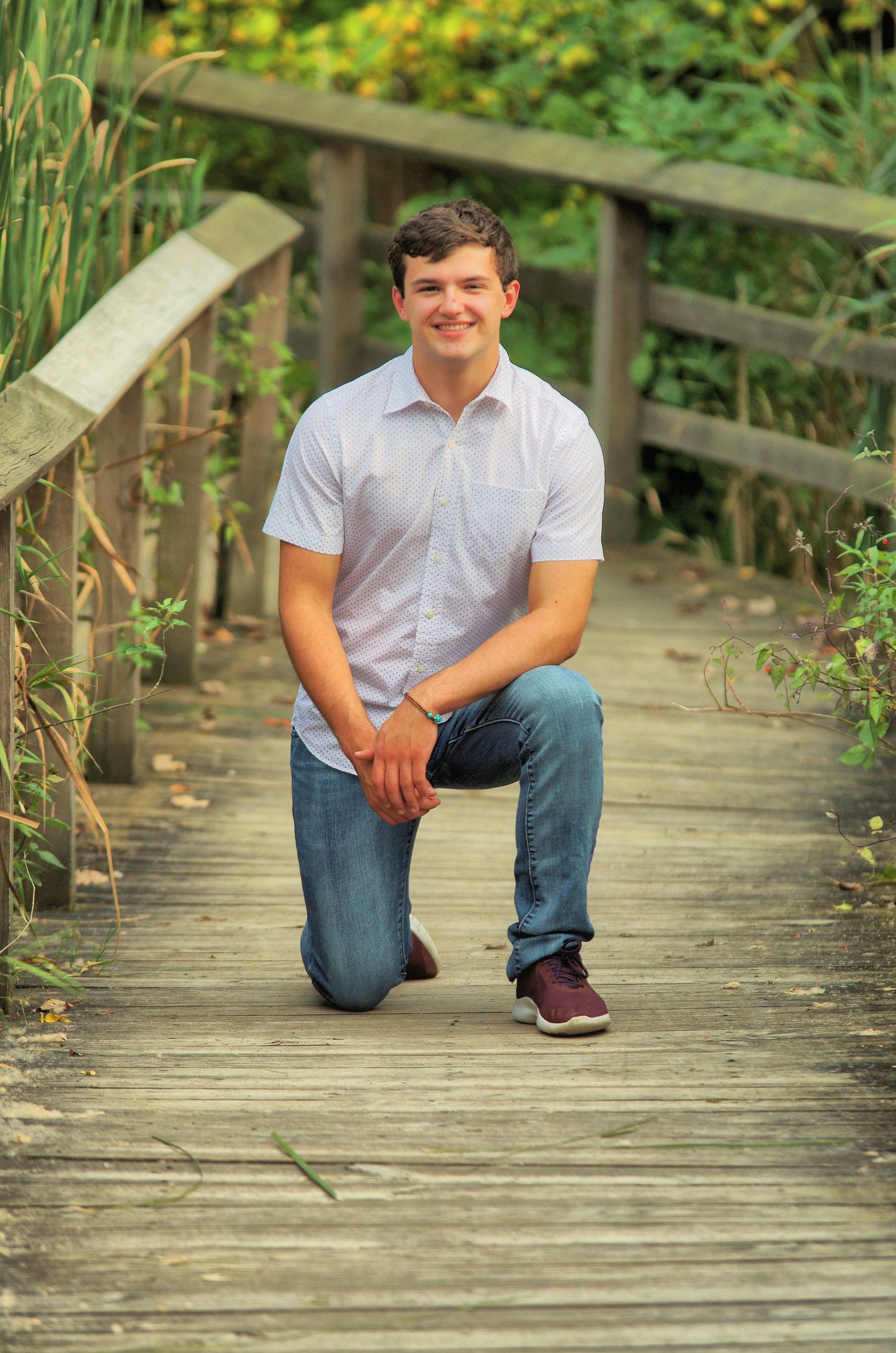 Casual portrait poses on a wooden boardwalk surrounded by lush greenery and cattails.