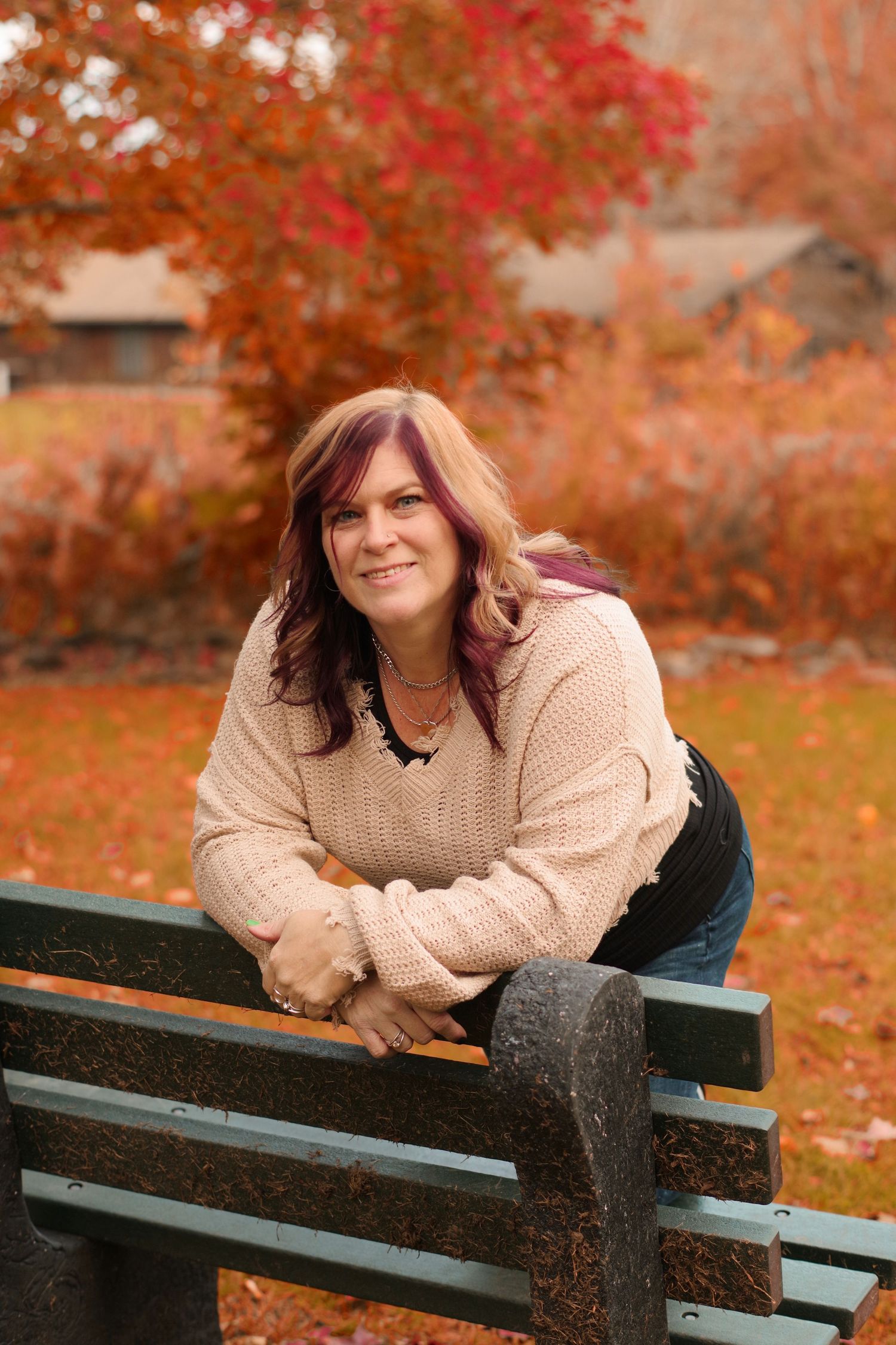 A cozy autumn portrait on a park bench with fall foliage and warm tones in the background.