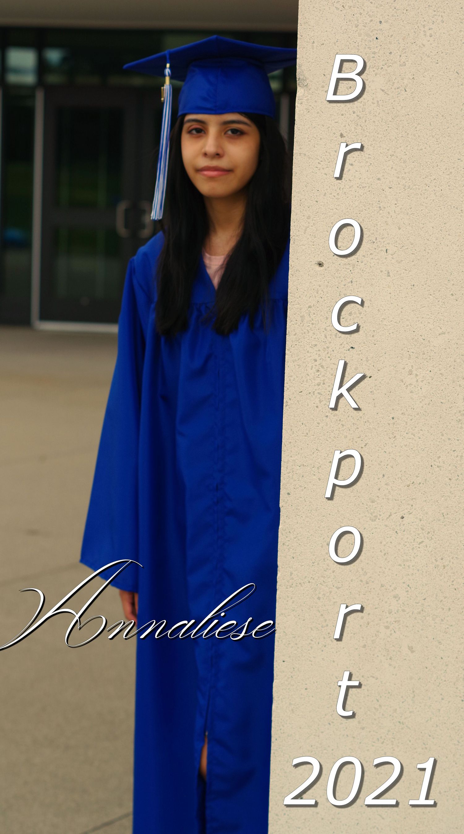 Graduate in blue regalia poses by architectural column with class year 2021.