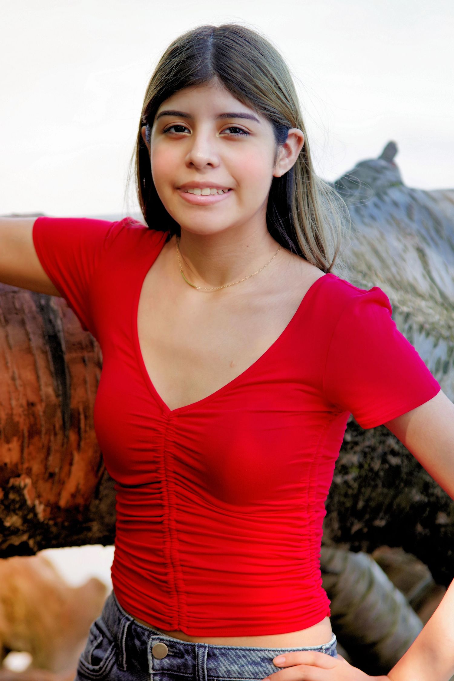 A portrait in a red top against a desert rock formation background.