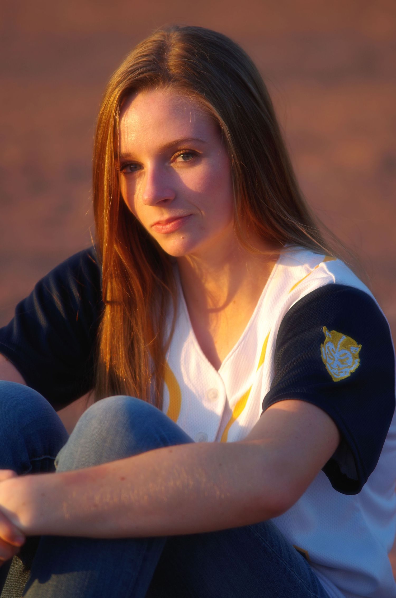 Sunset portrait in navy and white sports uniform during golden hour.