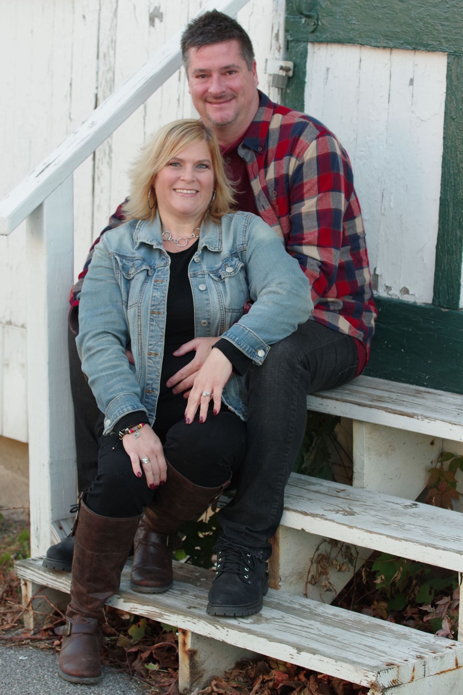 Casual couple posing on white wooden steps outdoors on a cool day.