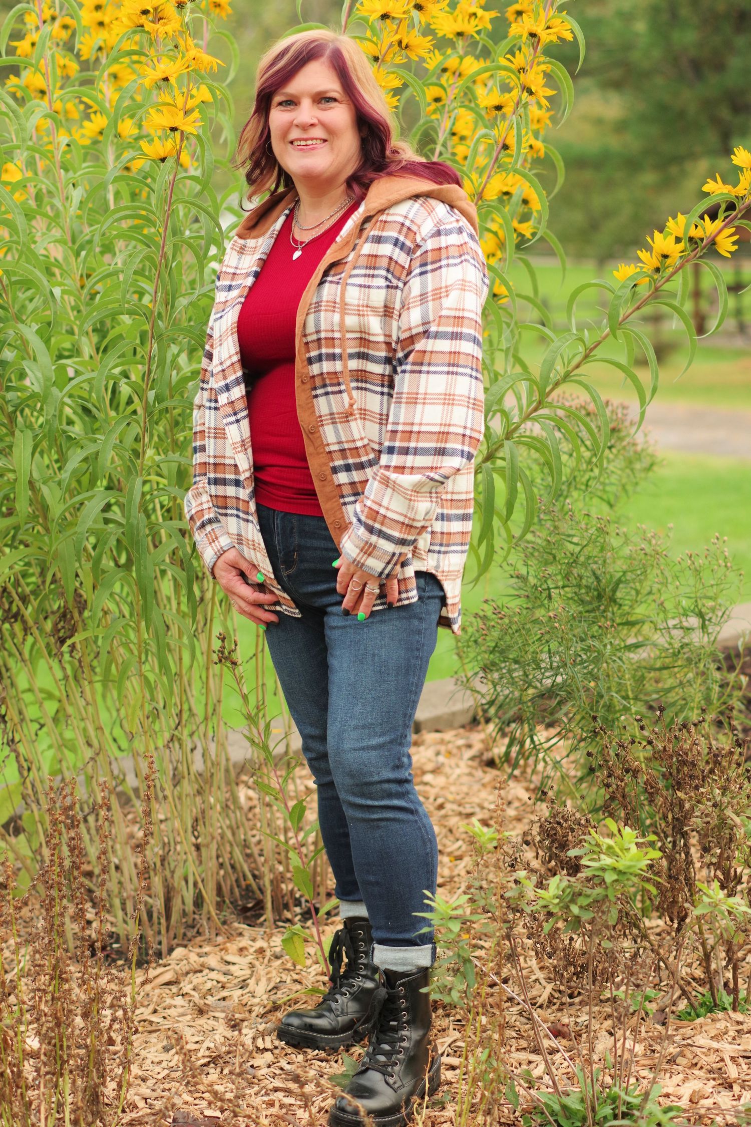 Casual outdoor portrait among yellow wildflowers wearing plaid shirt and red top.