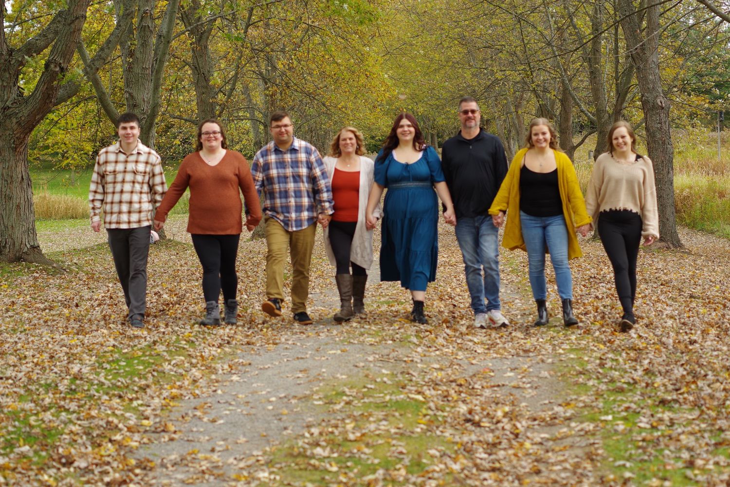 Group walking together on leaf-covered path through autumn woods.