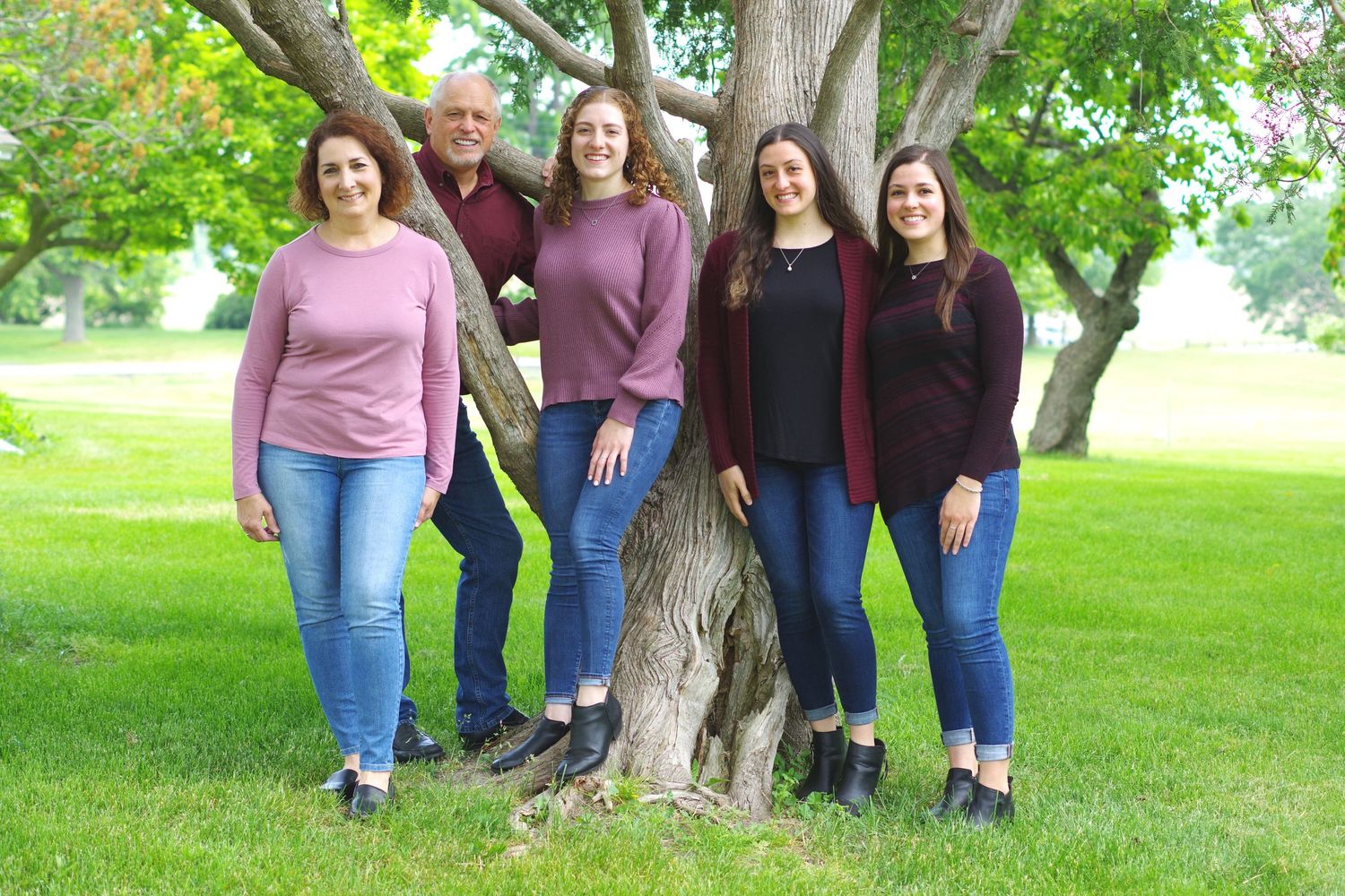 Casual group portrait by a tree in a sunny park setting.