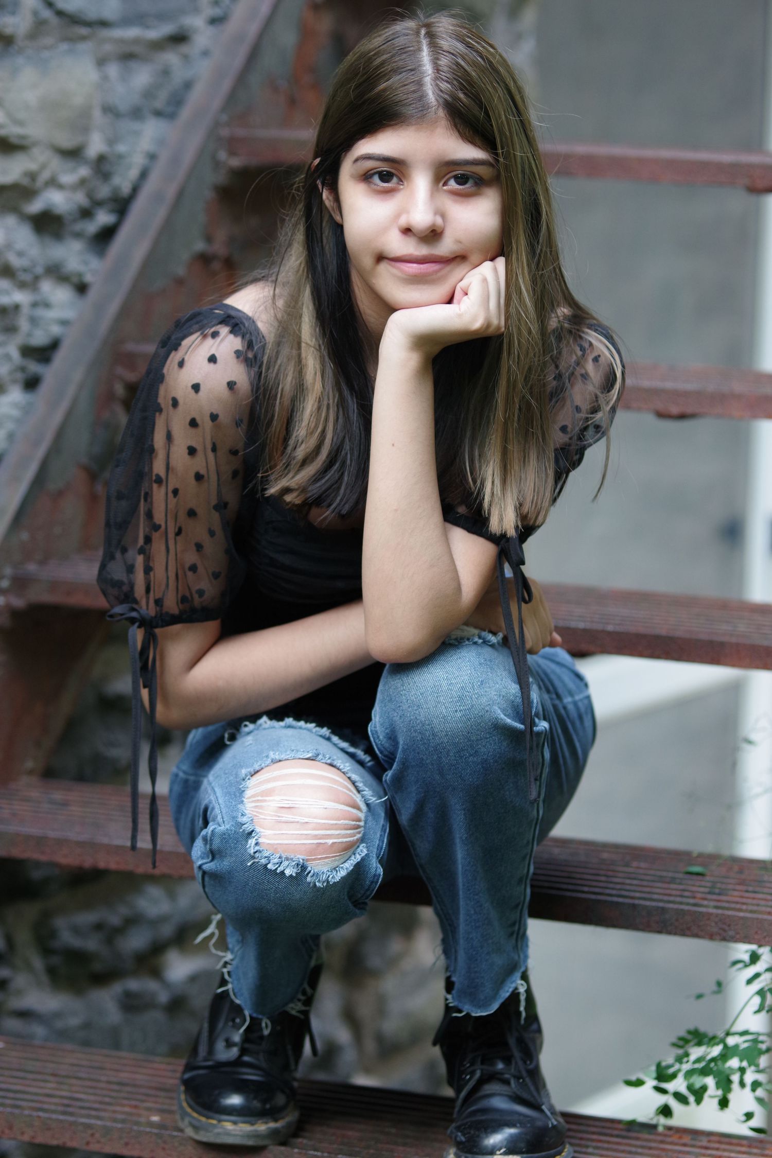 Candid portraits sitting on wooden steps in urban setting wearing distressed denim.