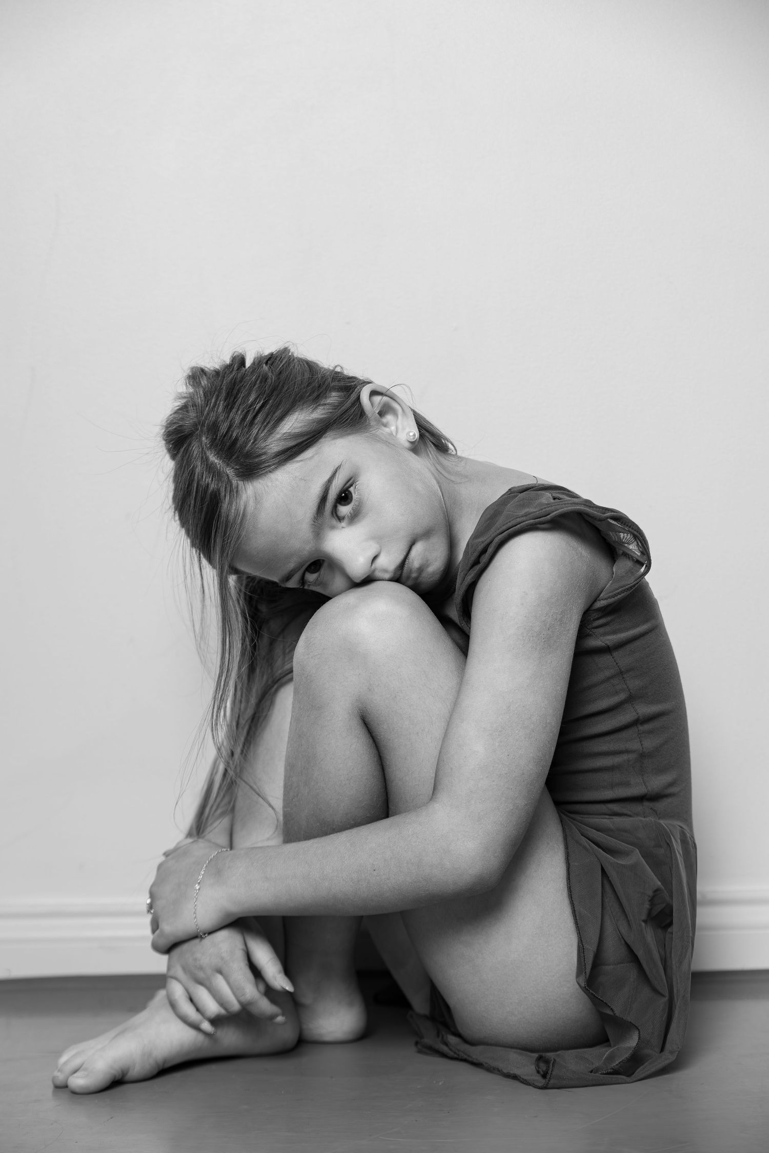 A young female dancer poses in a sitting position looking down the barrel of the lens.