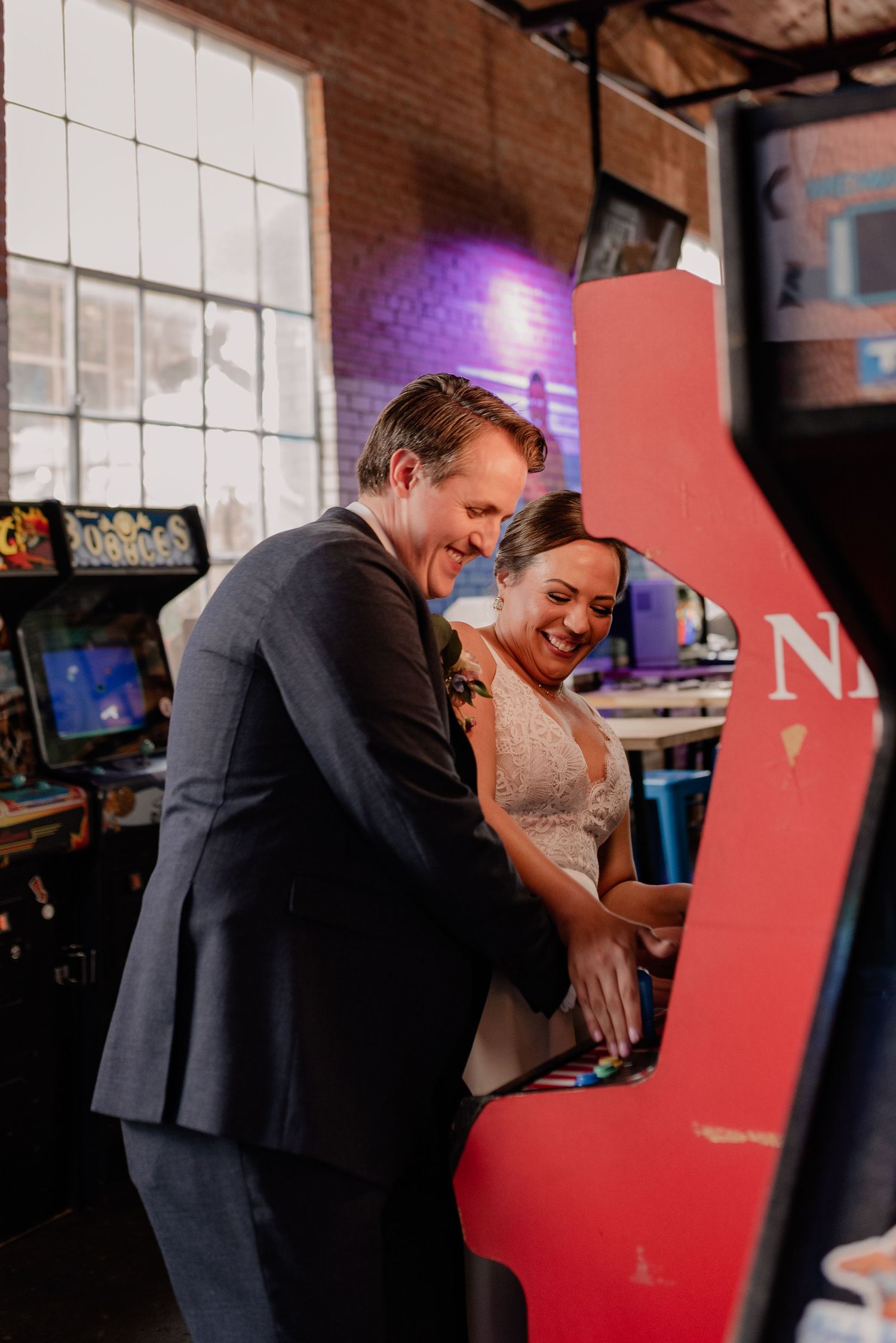 Wedding couple sharing a playful moment while playing classic arcade games at Retropub in Bishop Arts, Dallas, TX