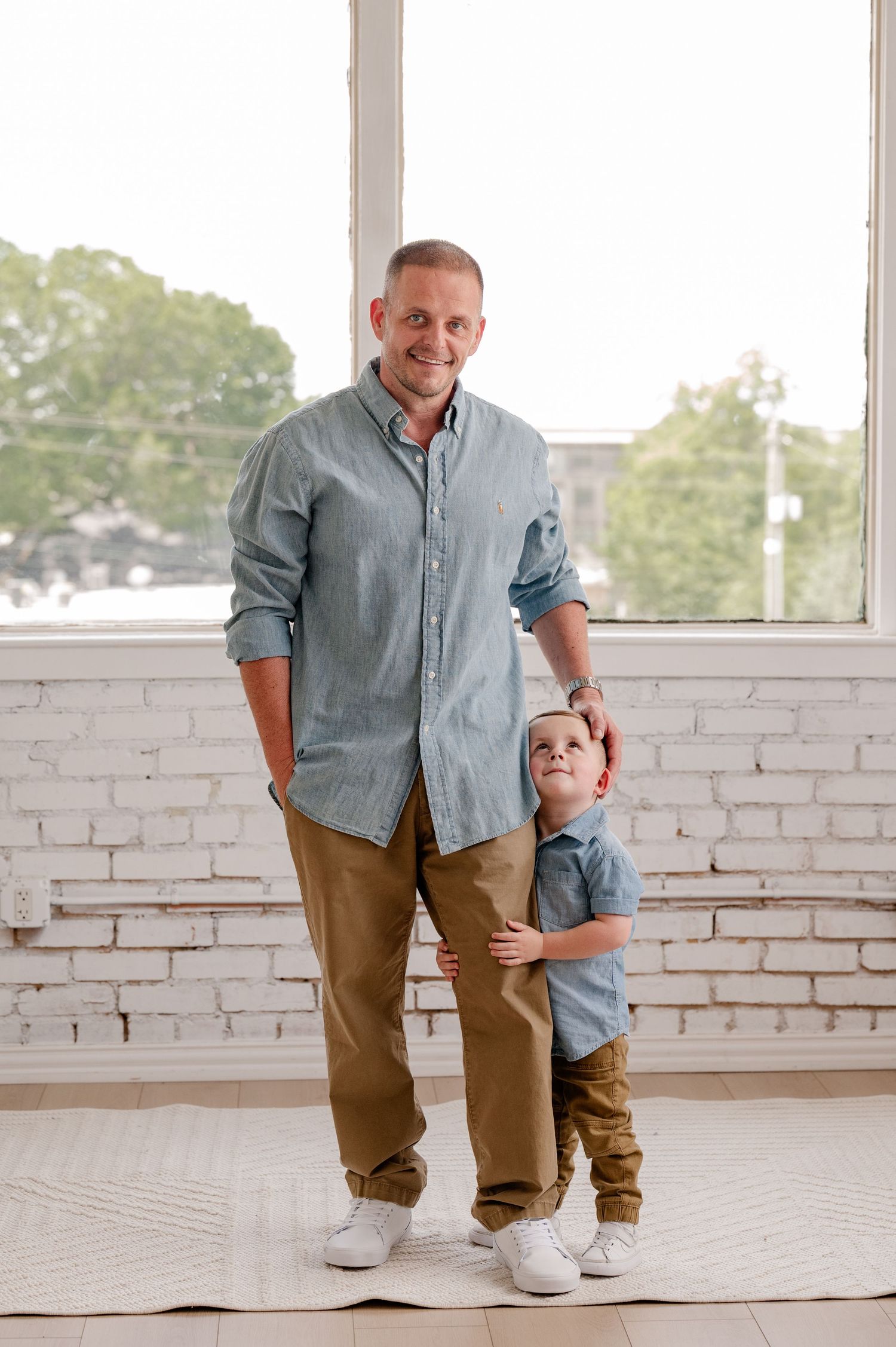 Sweet moment of son staring up at his dad at a family photo session in a bright, minimalist studio in Dallas, Texas