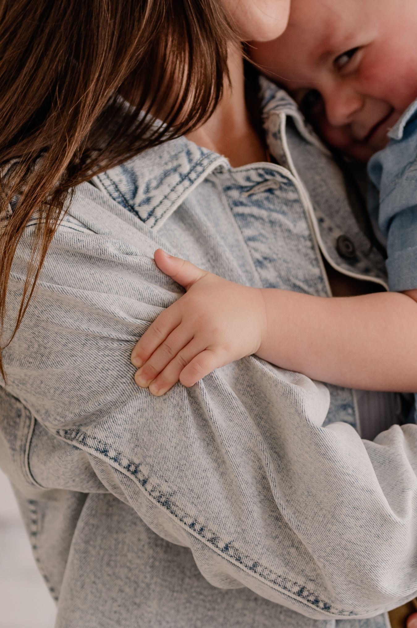 Close up lifestyle photo showing an affectionate embrace between mother and son in a bright indoor studio in Dallas, Texas