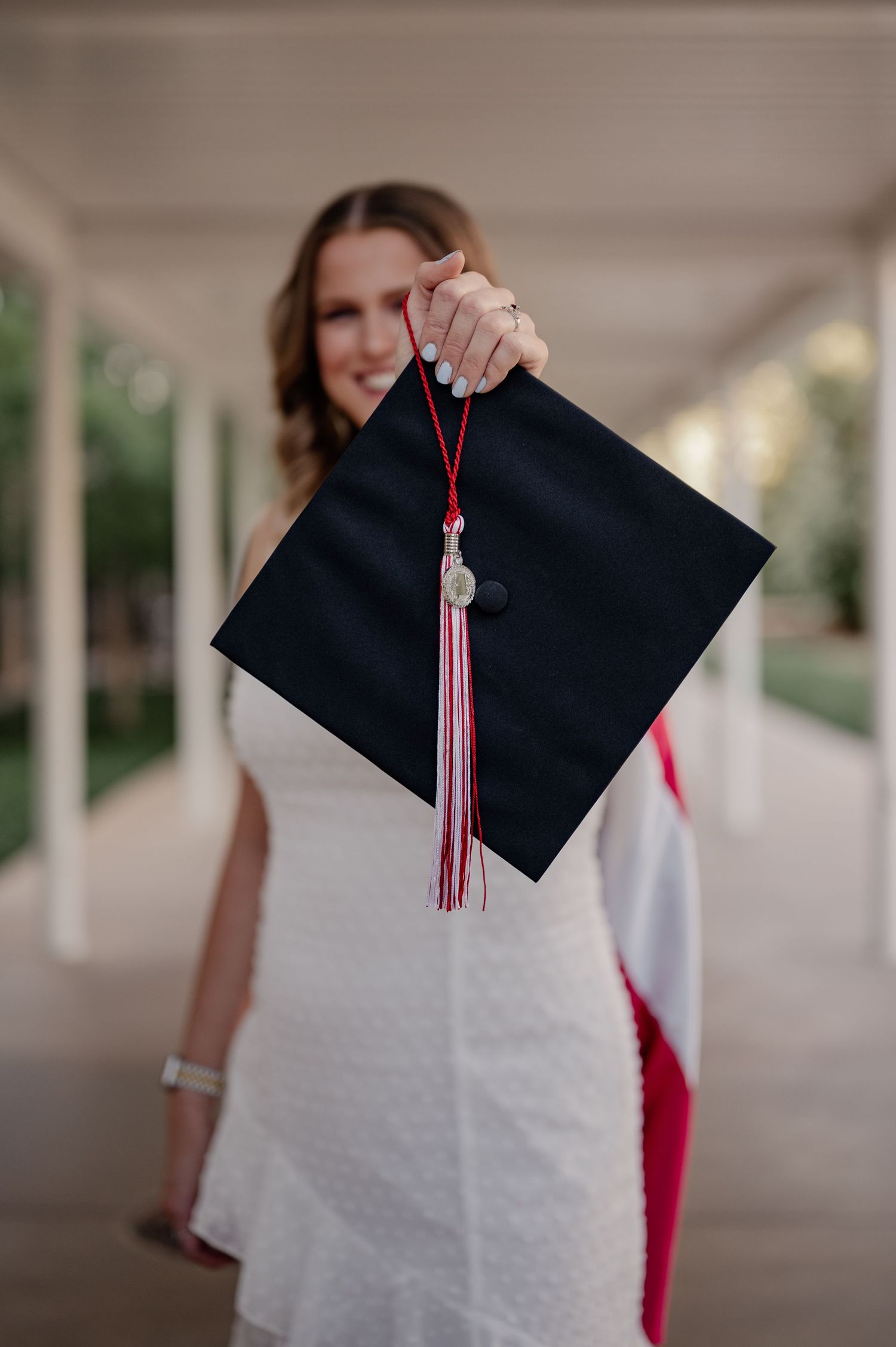 College senior girl posing with her cap and stole at University of Texas at Dallas for a fall senior photo session
