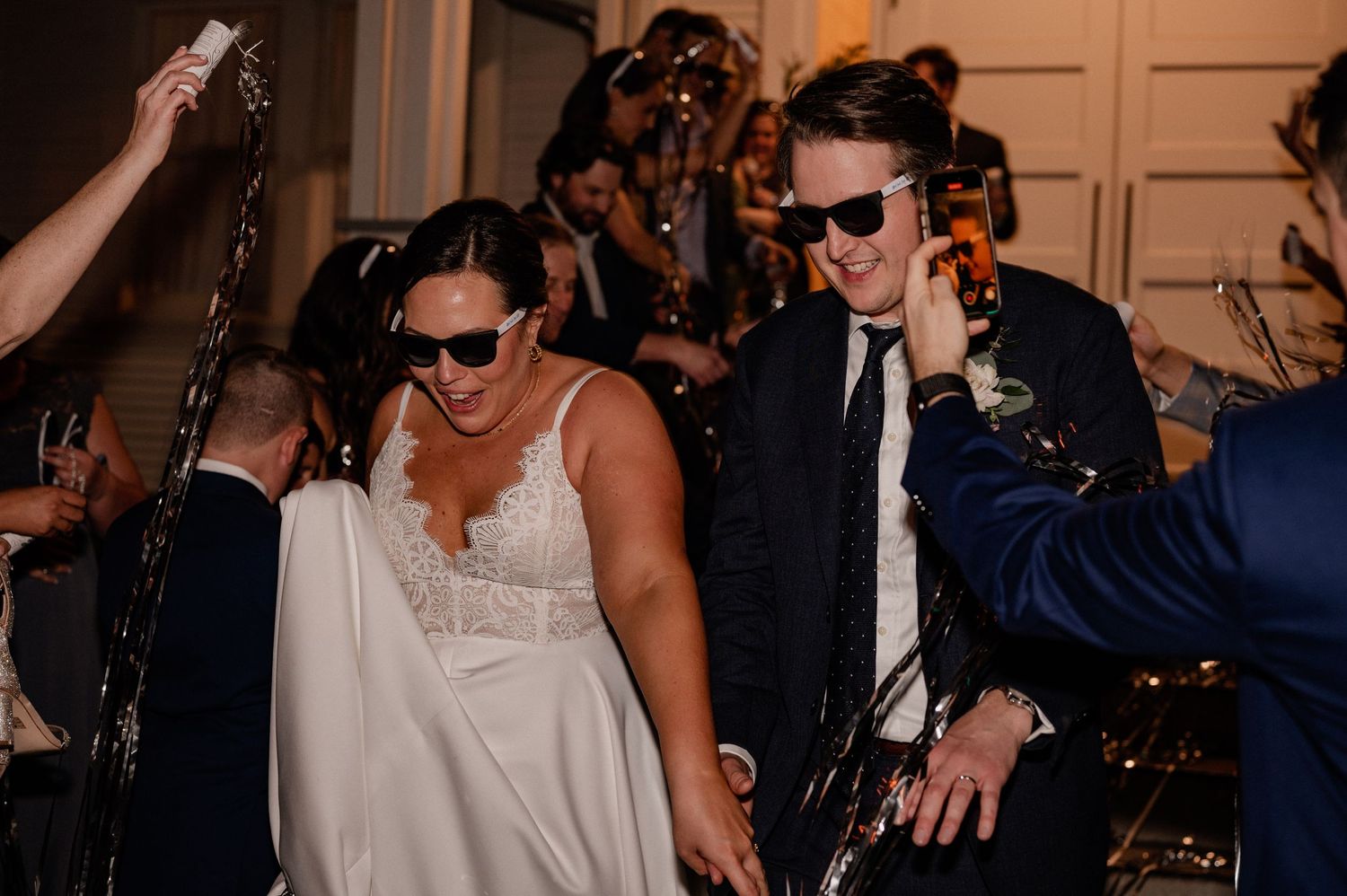 Bride and groom make a hurried grand exit in sunglasses at night time outside of historic Bishop Arts venue in Dallas, Texas