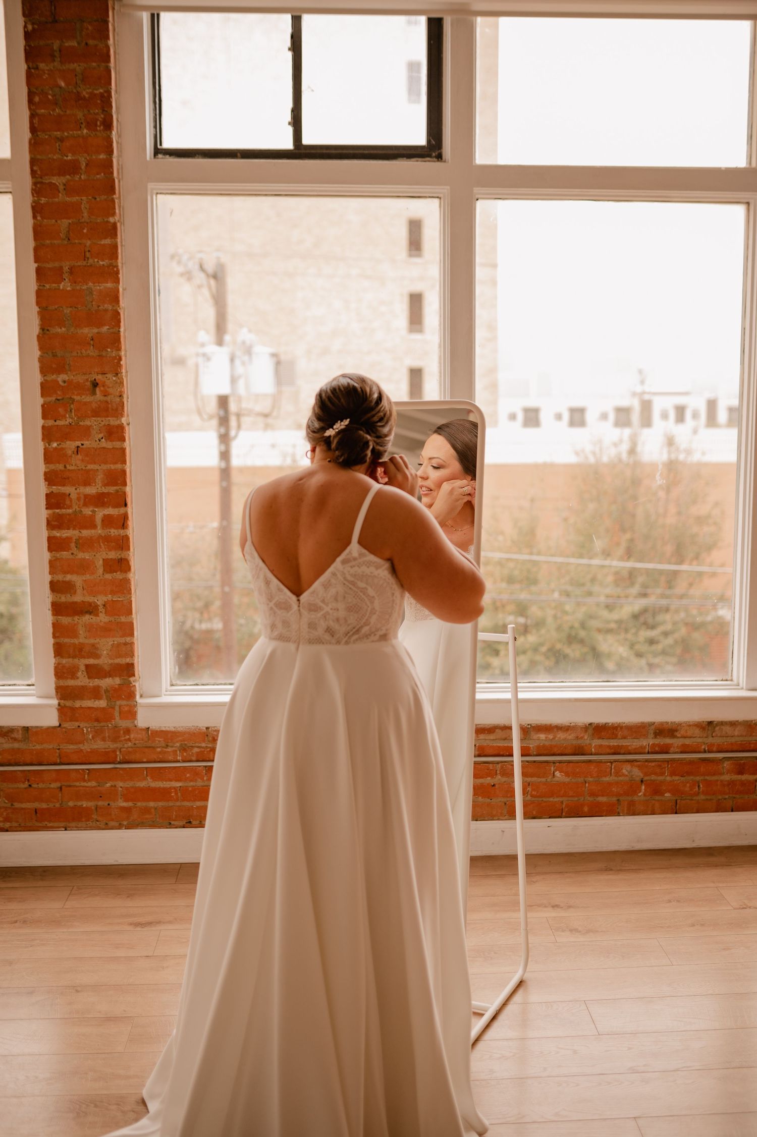 Bridal gowns displayed in bright studio with exposed brick walls.