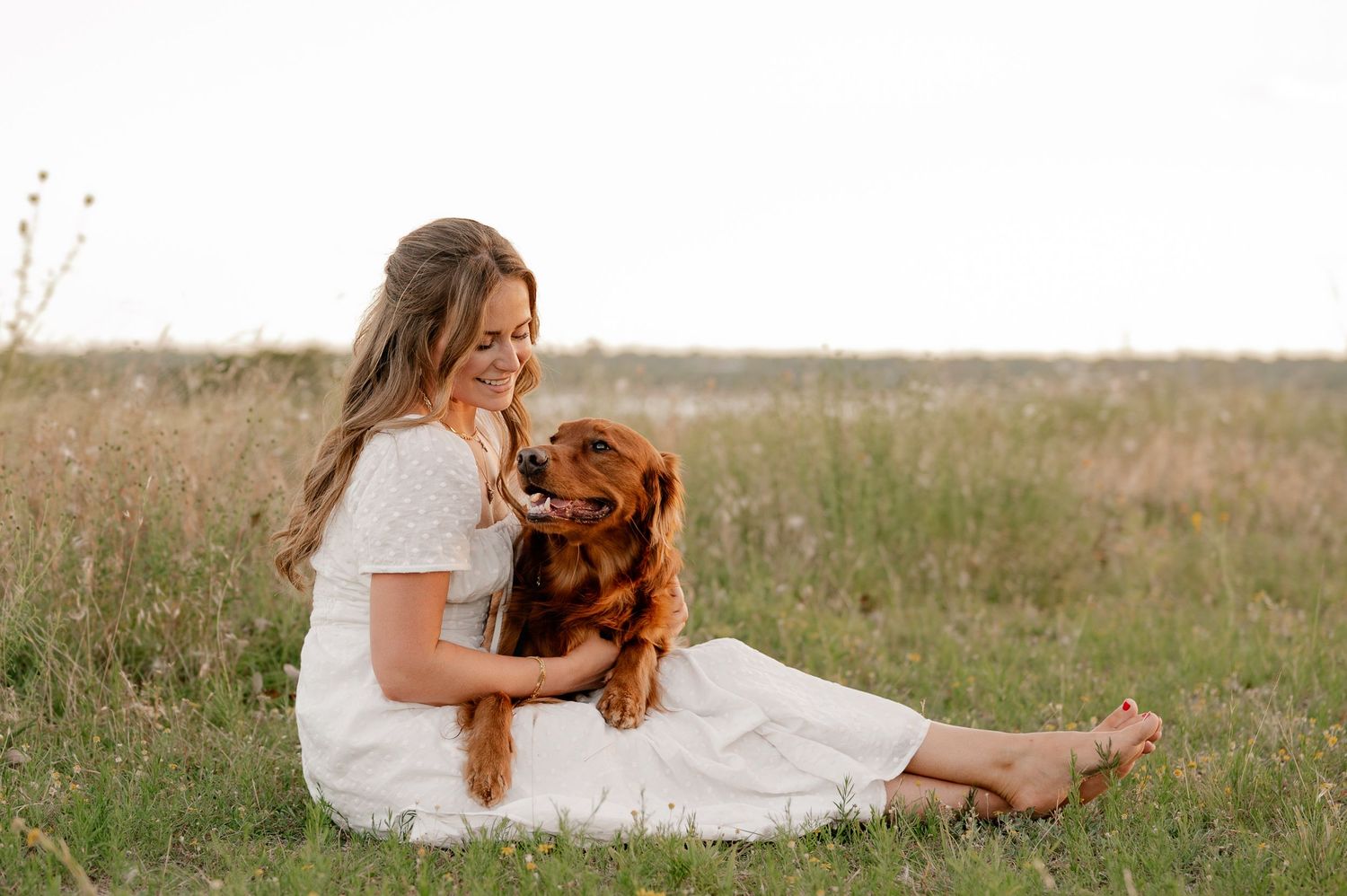 Candid lifestyle portrait of a girl and her dog sitting in a field overlooking White Rock Lake in East Dallas, Texas