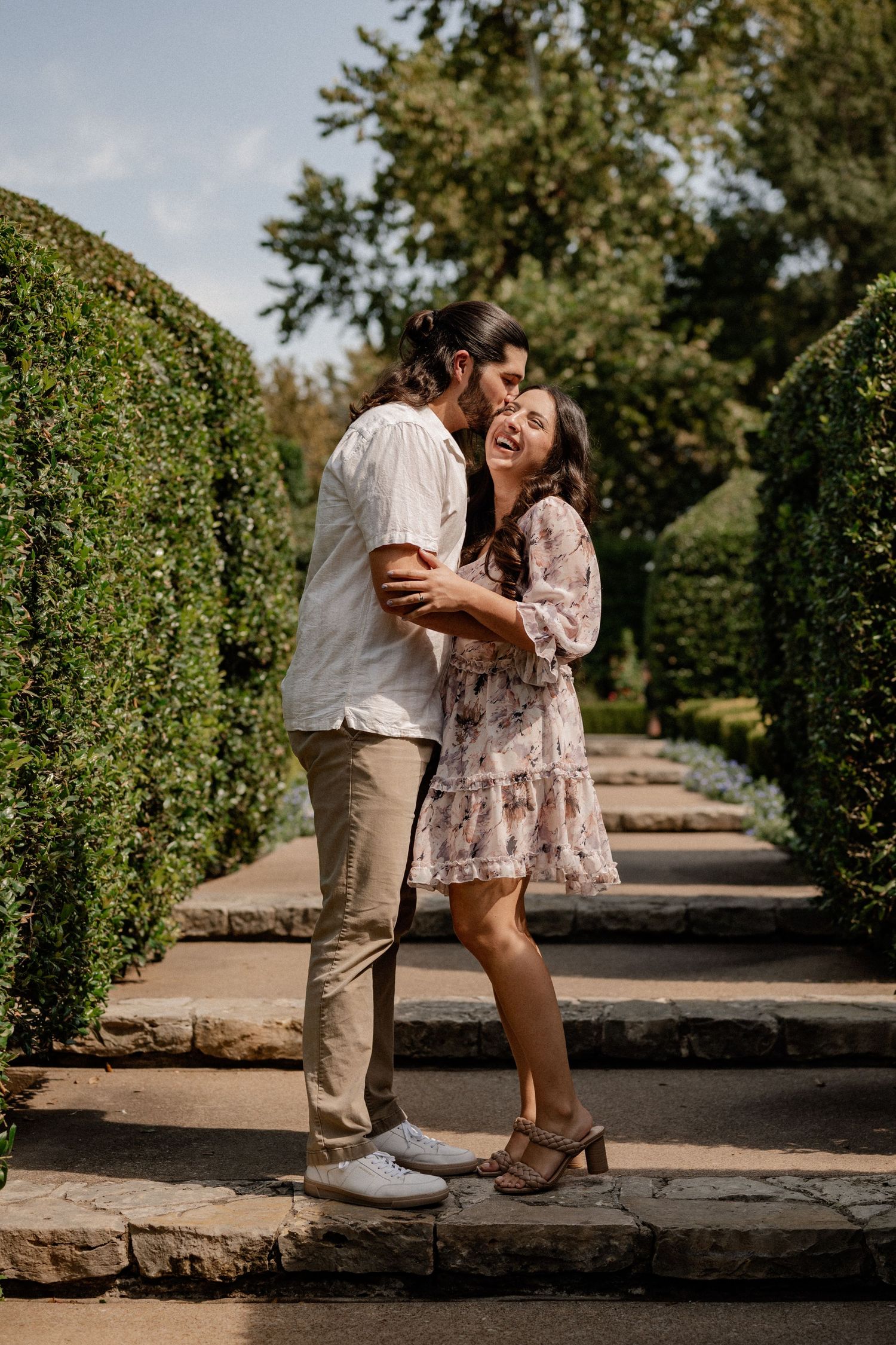 Couple joyfully embracing and laughing during a proposal couple's session at the Dallas Arboretum in East Dallas
