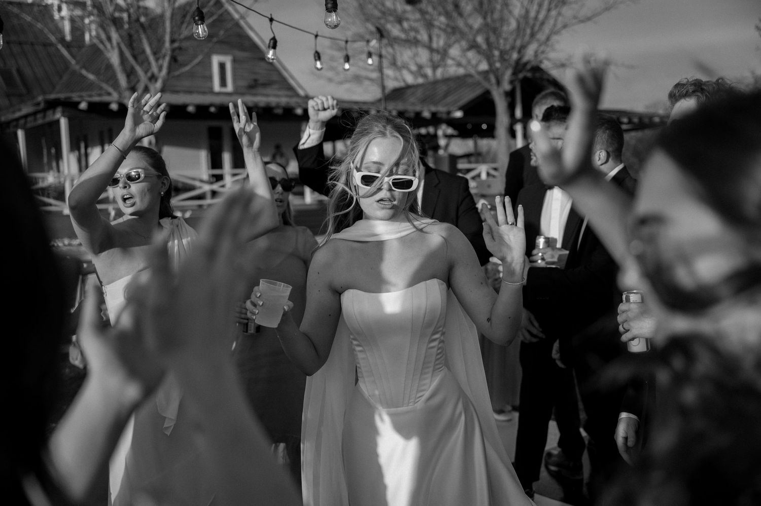 Black and white candid of a bride with sunglasses on in the middle of an outdoor reception dance floor for a Spring wedding