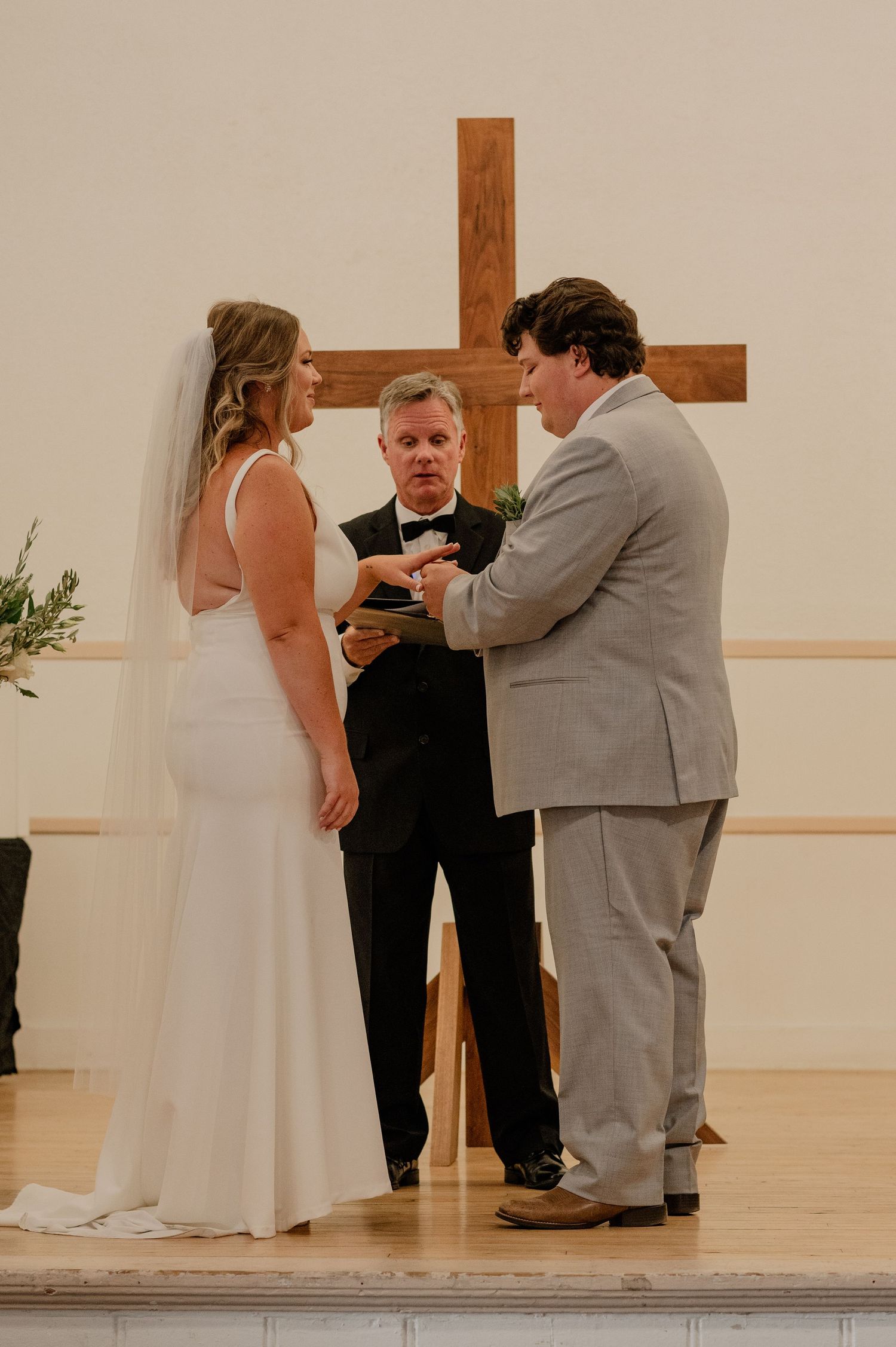 Wedding ceremony taking place in front of a wooden cross with minimalist decor.