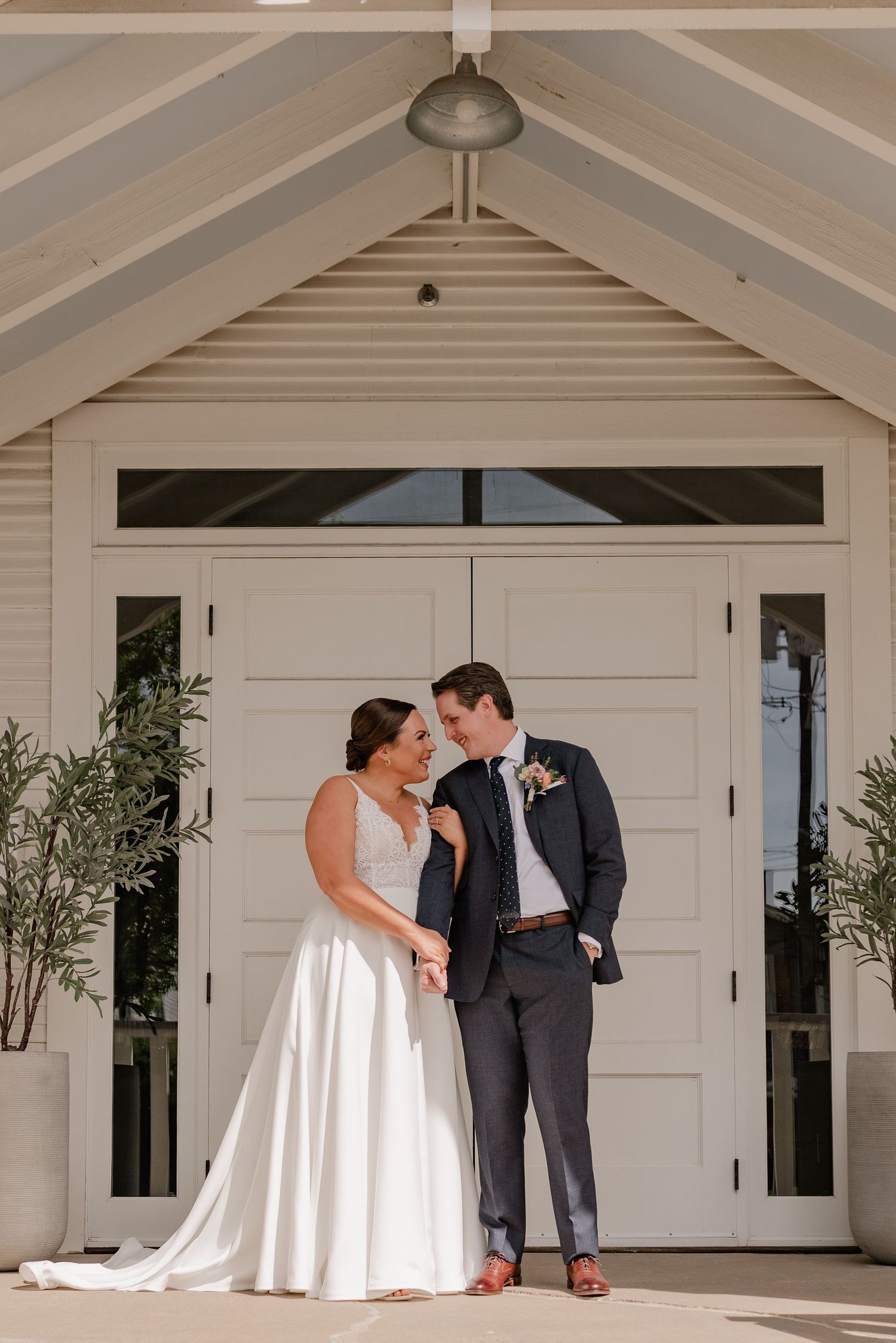 A wedding couple shares a sweet first look moment on a white porch with elegant details and natural lighting.
