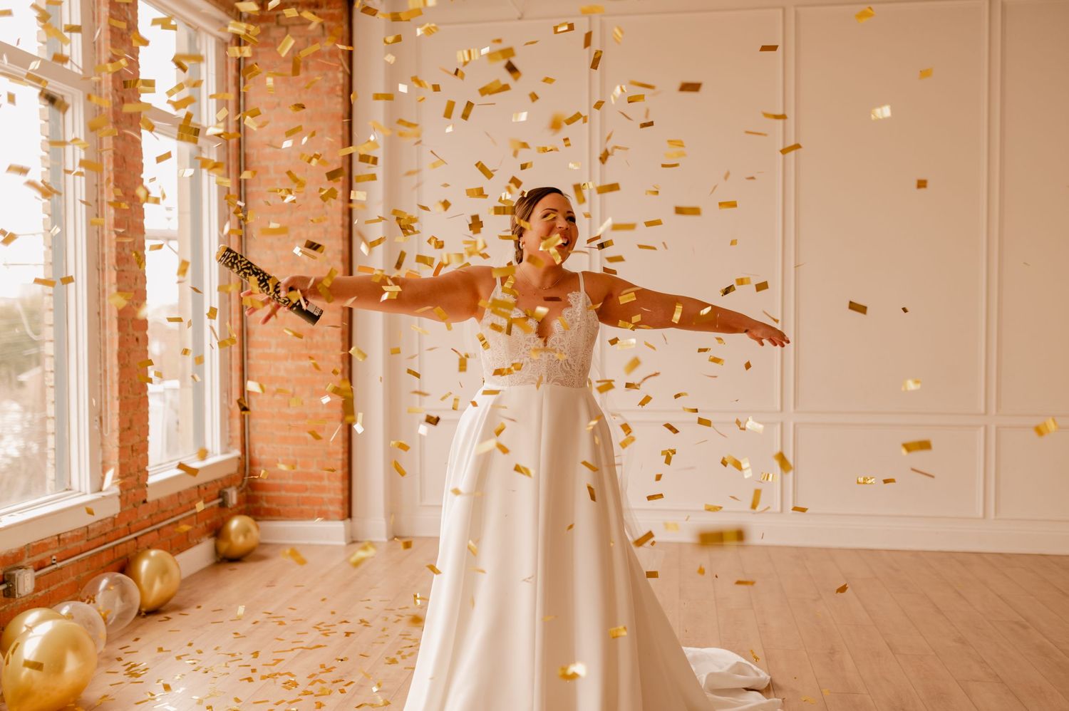 Dancing figure in white gown spins under a shower of gold confetti in a sunlit studio.