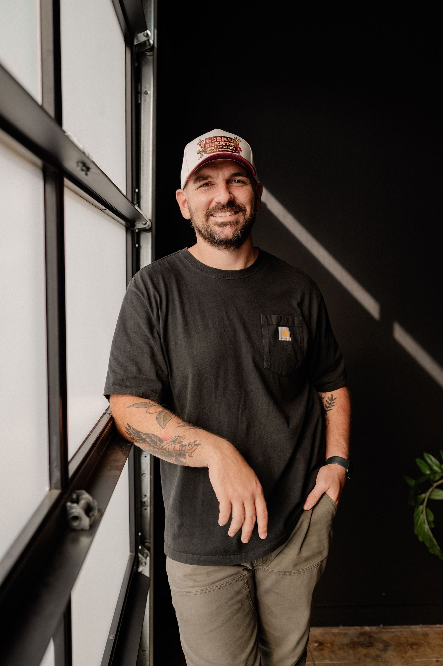 Branding headshot of a male photographer dark colors in front of a black wall at a studio in Richardson, Texas