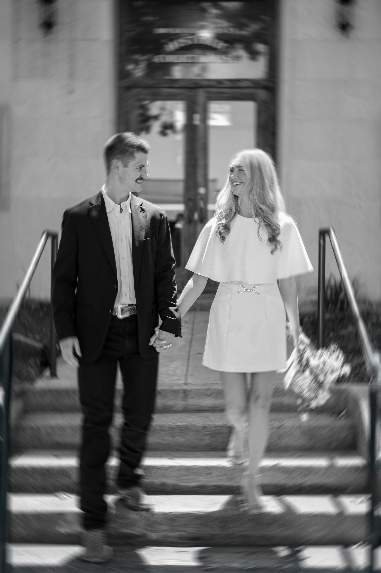 Black and white playful married couple outside of downtown Rockwall courthouse during elopement wedding photo session