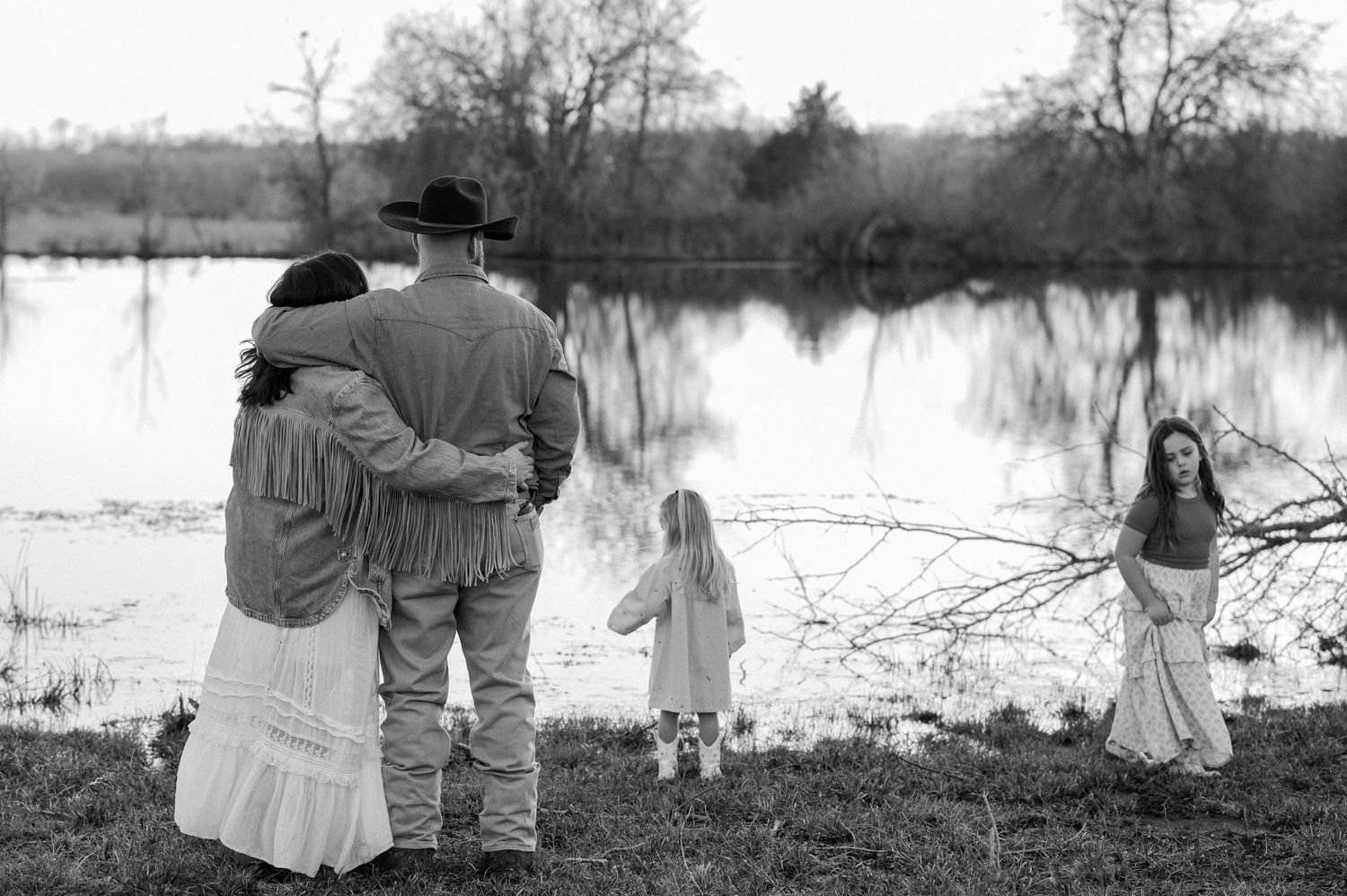 Candid lifestyle photo of a playful at an at-home family session in front of a large pond on their farm in Greenville, TX
