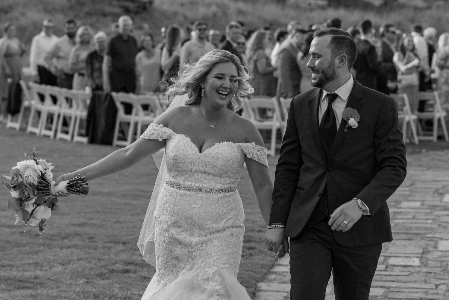 Black and white whimsical candid photo of Bride and Groom exiting an outdoor summer wedding ceremony in Fort Worth, Texas