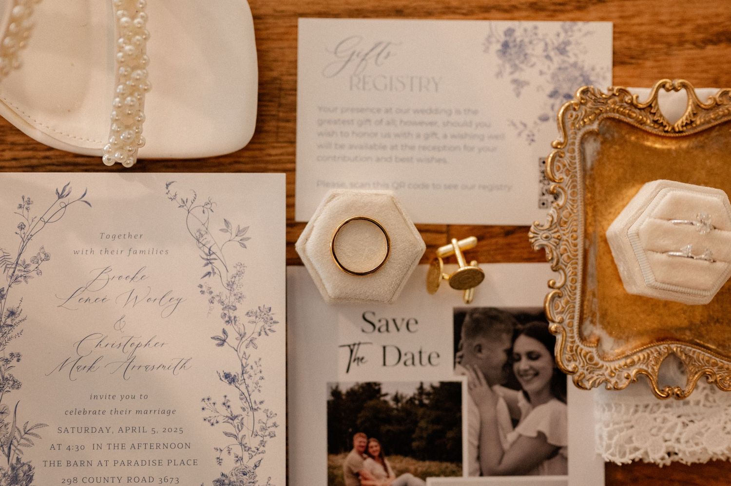 Elegant wedding flat lay featuring floral invitations, save the date card, gold rings, cufflinks, and a vintage ornate tray