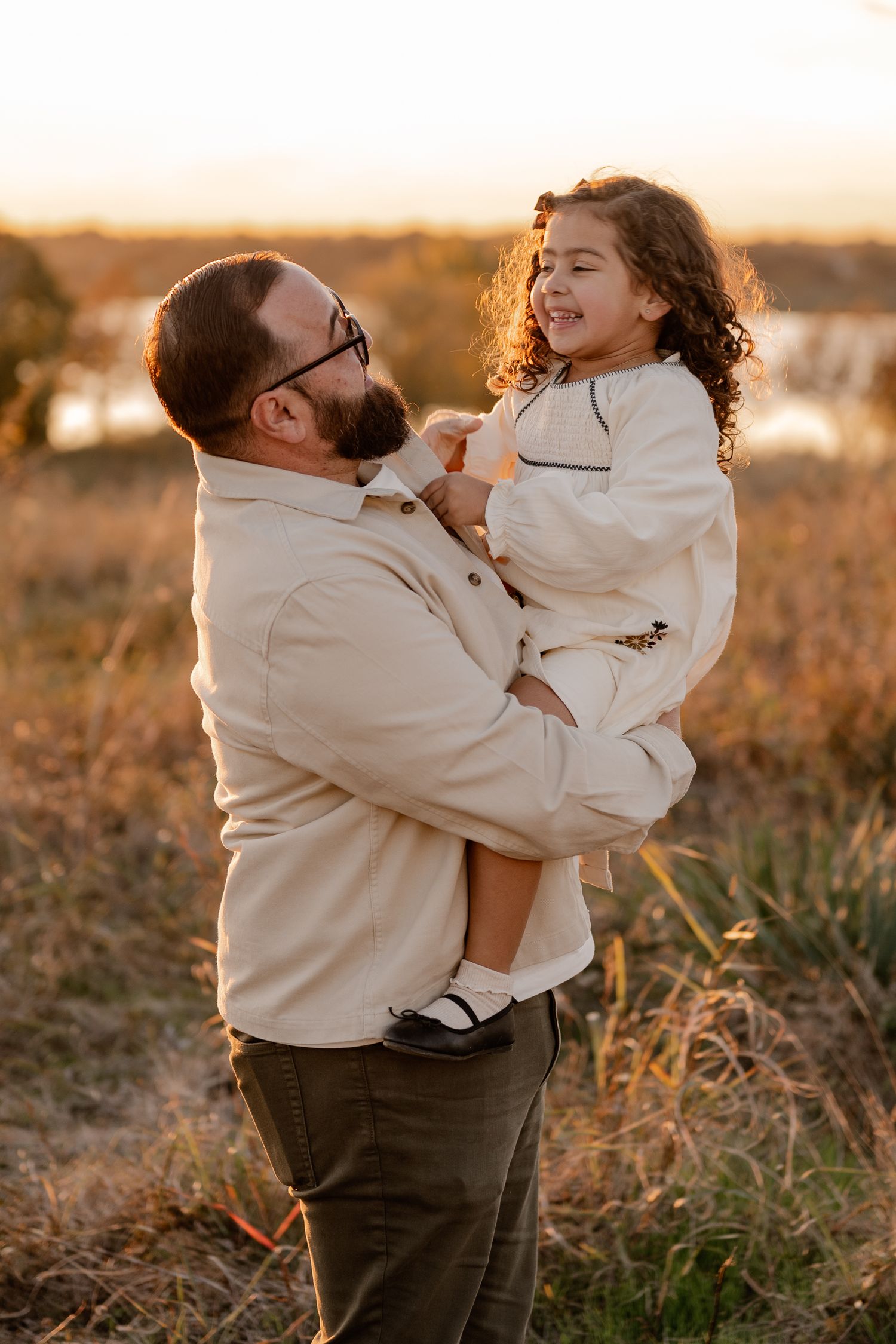 Father and daughter candidly playing at golden hour overlooking the White Rock Lake in East Dallas, Texas