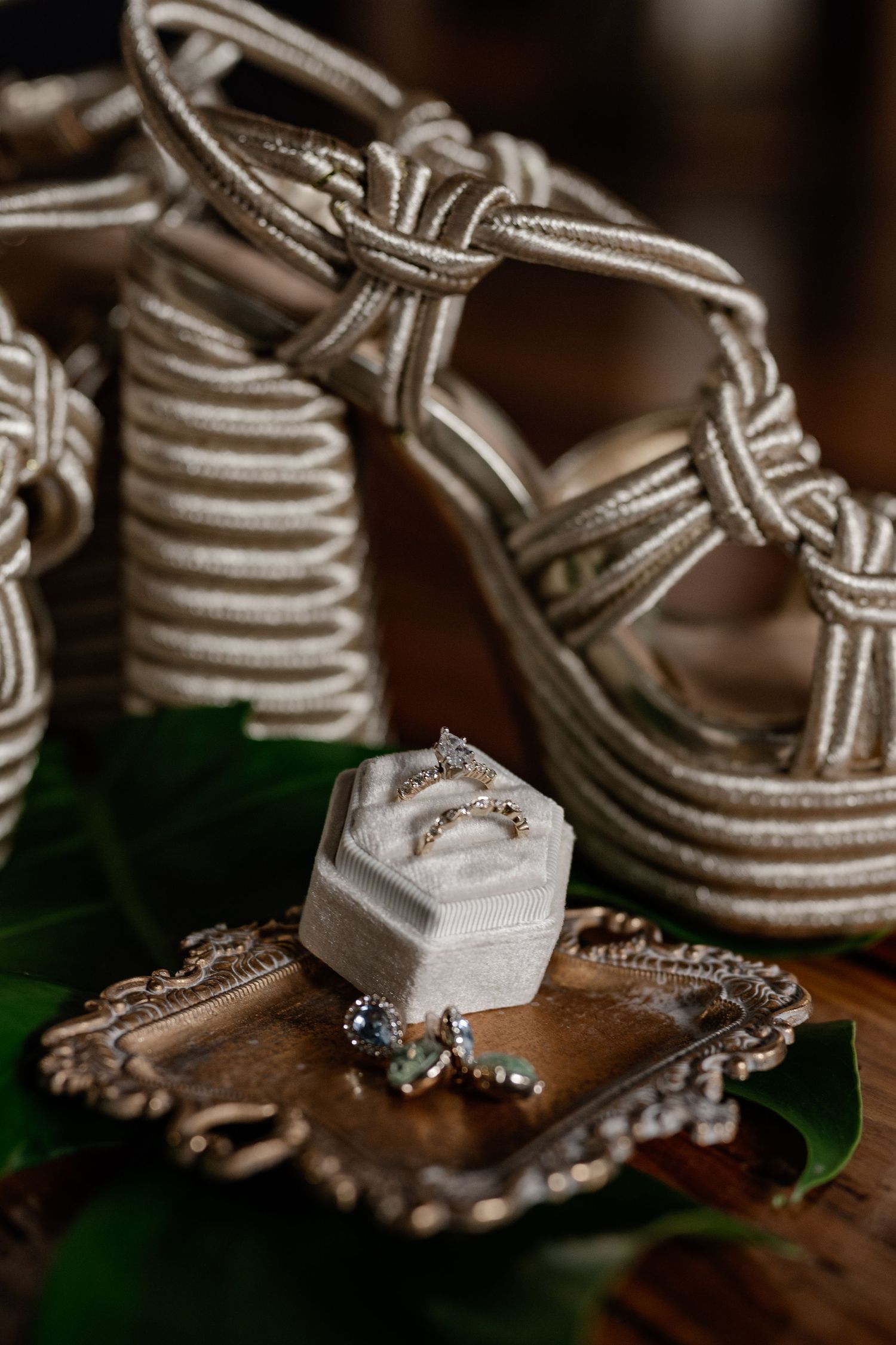 Close-up shot of elegant wedding rings with wedding shoes in soft focus creating romantic wedding detail photography.