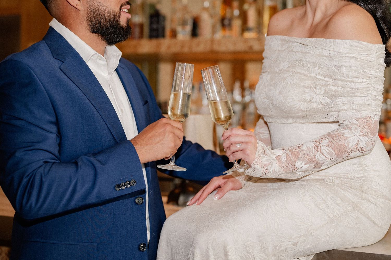 Couple toasting flutes in formal wear at a downtown Dallas rooftop bar for an indoor engagement photo session