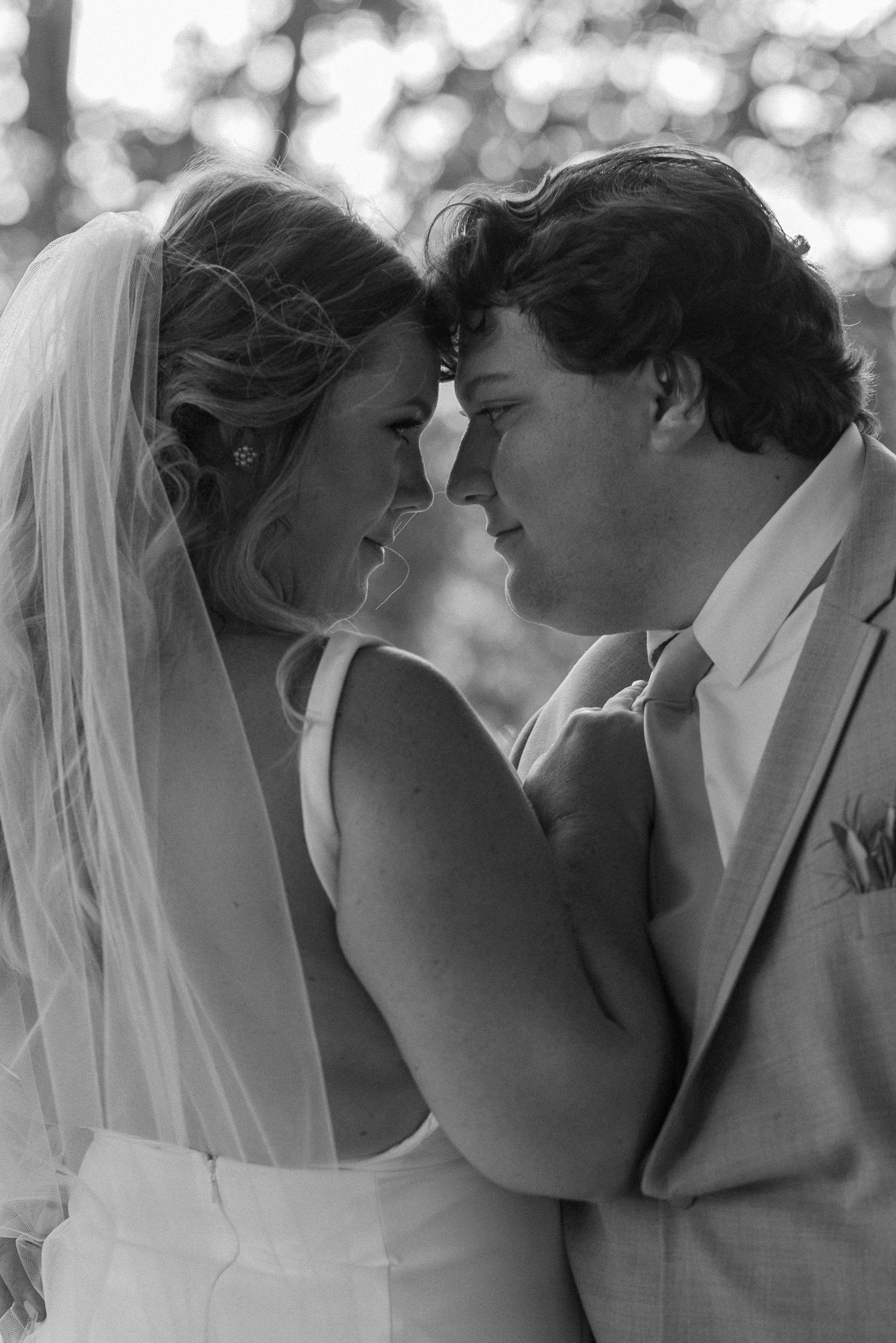 Intimate black and white portrait of newlyweds sharing a tender moment.