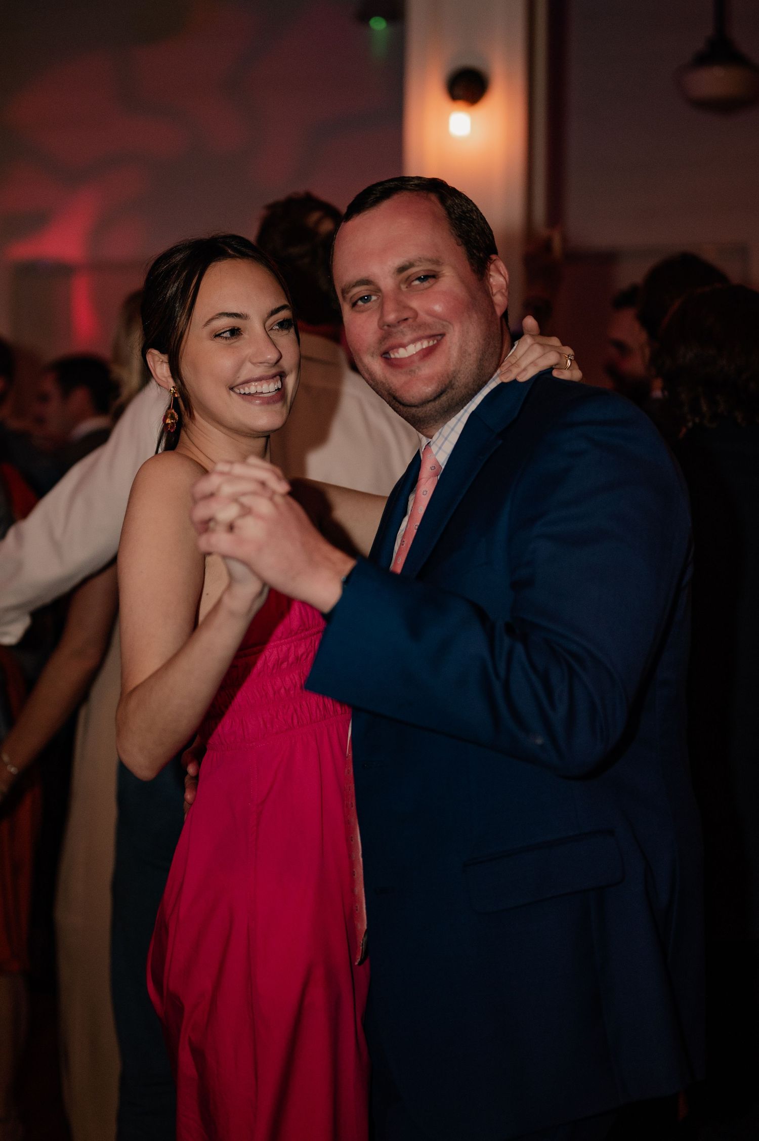 Couple dancing and posing together at wedding reception with dim lighting