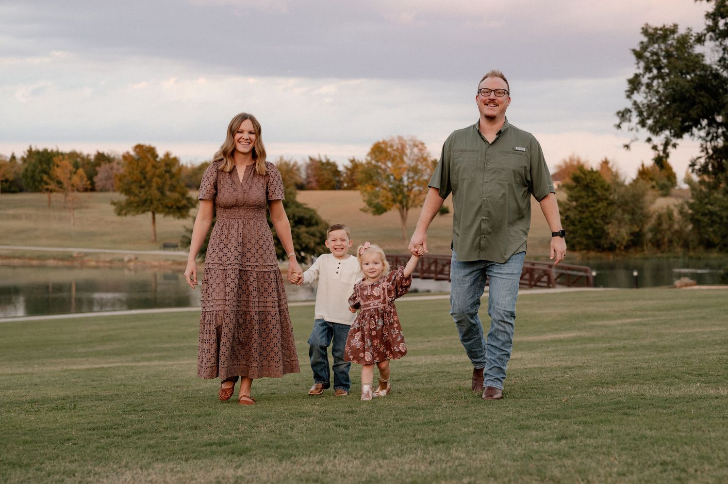 Family joyfully walking hand in hand in an open field at dusk for a fall family photo in Rockwall, Texas