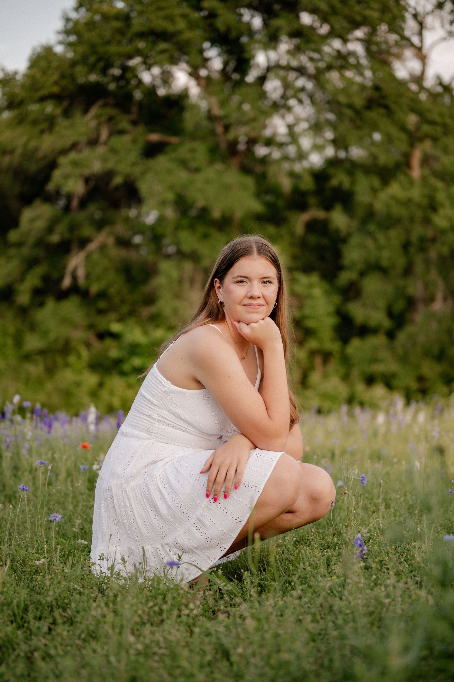 Senior girl casually posing in vivid wildflowers for a Spring senior photo session in Richardson, Texas