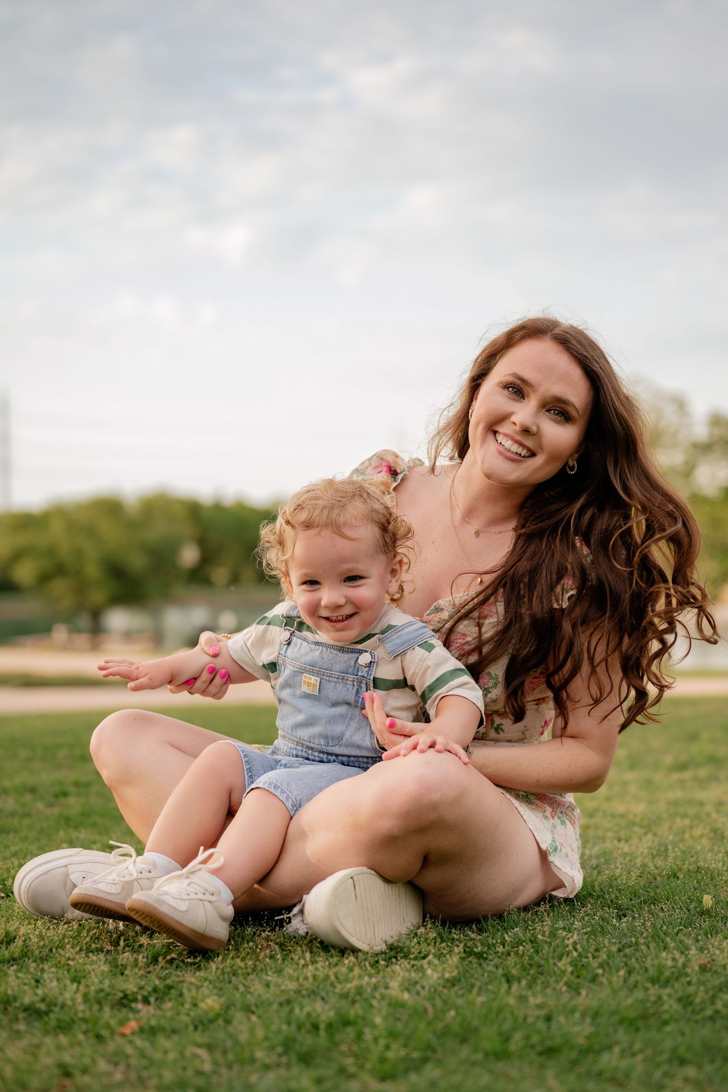 Mother and son sitting and posing for Spring family photos in vivid colors at large green park  in Rockwall, Texas