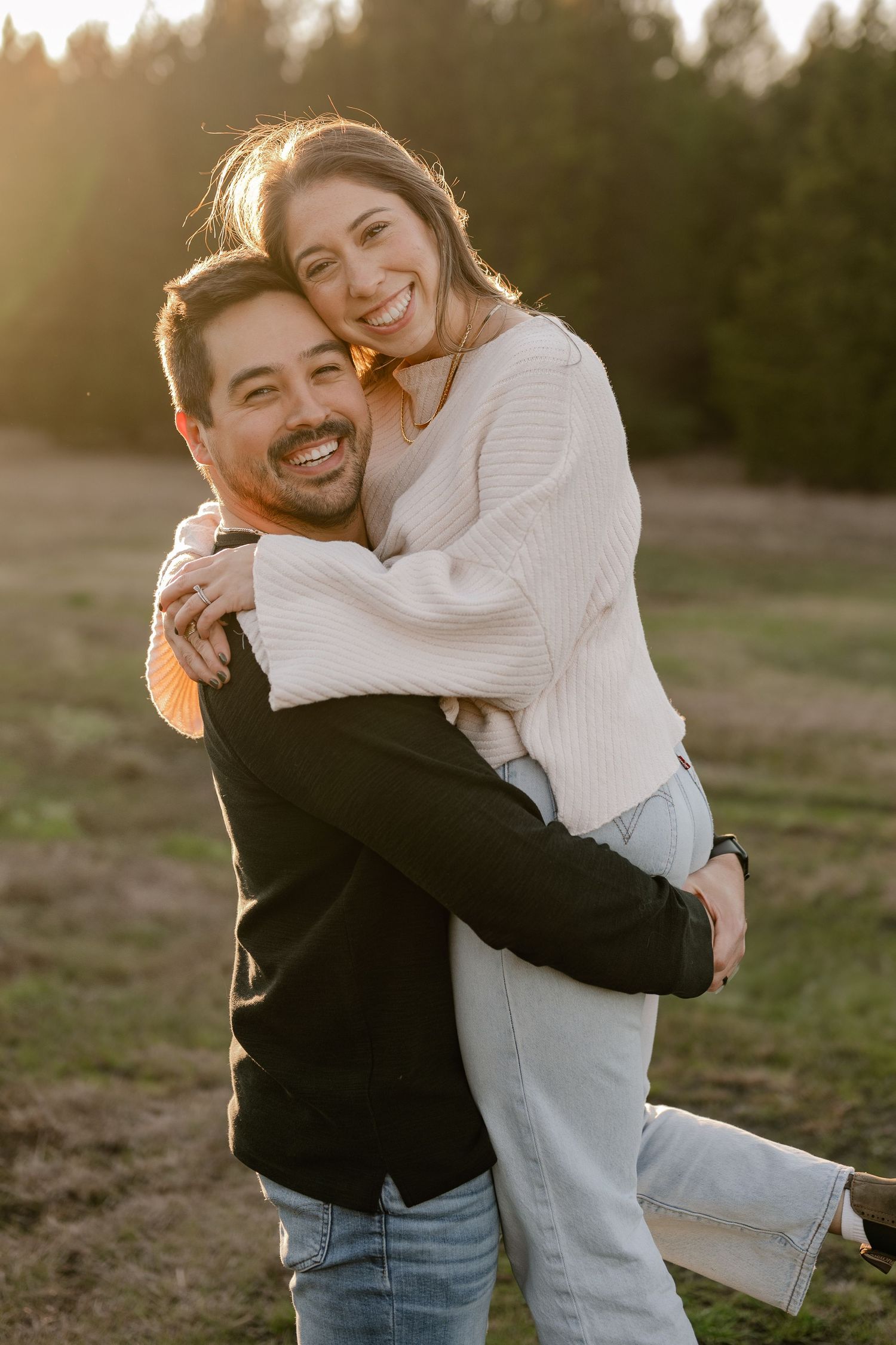 Joyful couple playfully hugging at a couple's photo session in a large tree lined field in Sunnyvale, Texas
