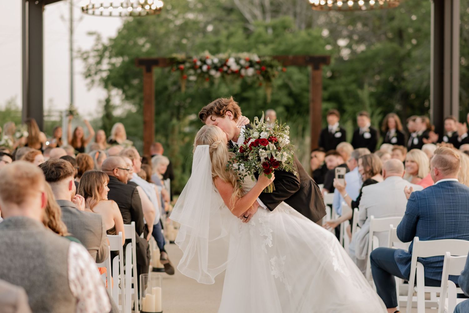 Intimate close-up photo of Bride & Groom kissing at the end of the wedding ceremony aisle in an outdoor wedding ceremony in Rockwall, Texas