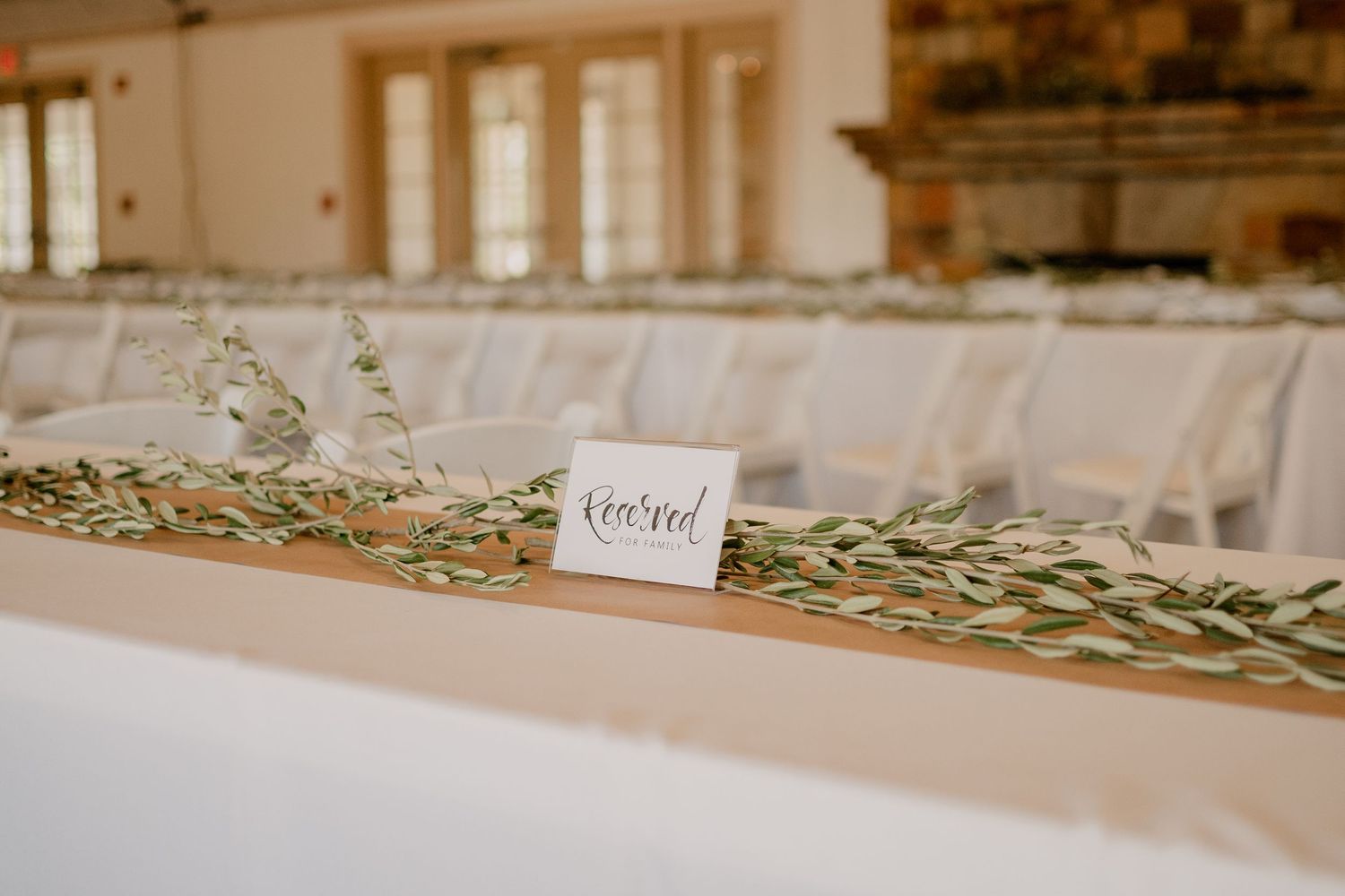 Elegant wedding reception table with eucalyptus garland runner and place cards.