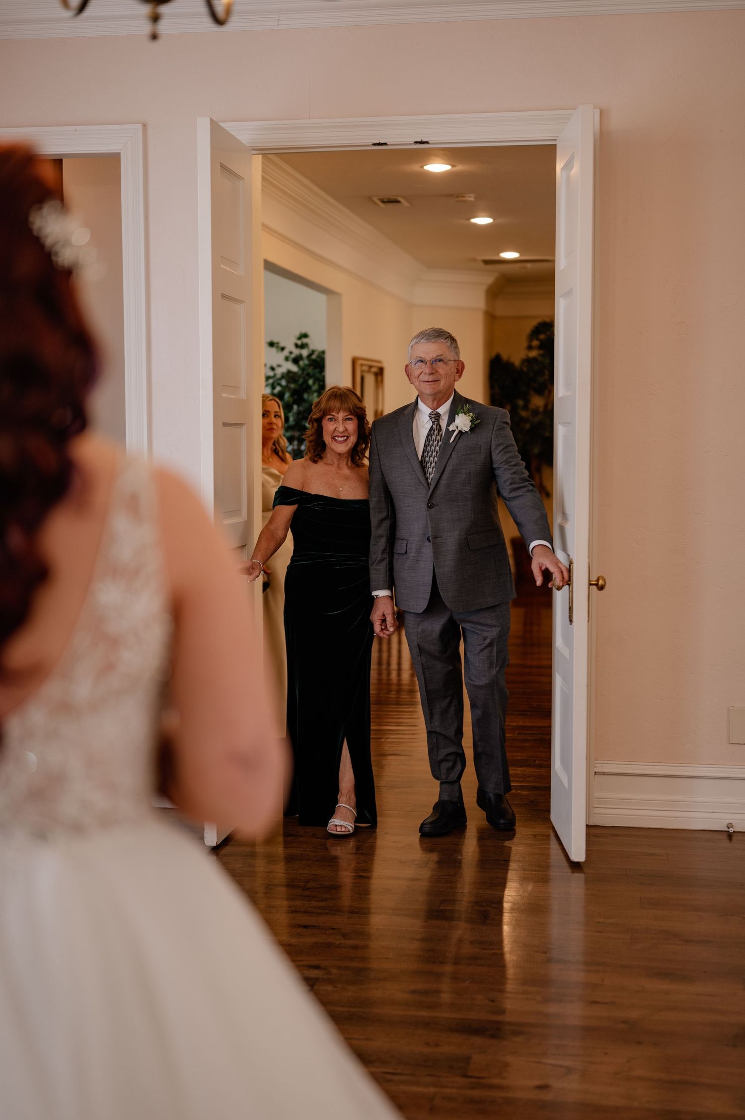 Bride's mom and dad stepping into bridal suite to see the bride in her wedding gown for the first look.