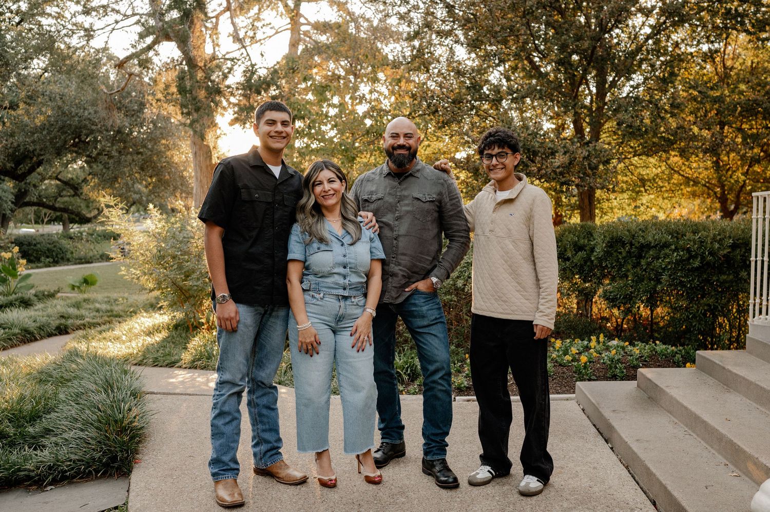 Family posed standing in a line at a lush green park in Dallas Texas for their fall family photos