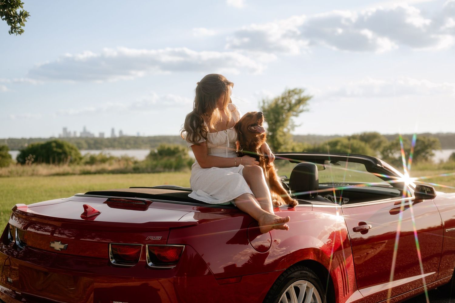 Vintage style portrait of a girl and her dog sitting off the back of her red convertible overlooking White Rock Lake in East Dallas, Texas