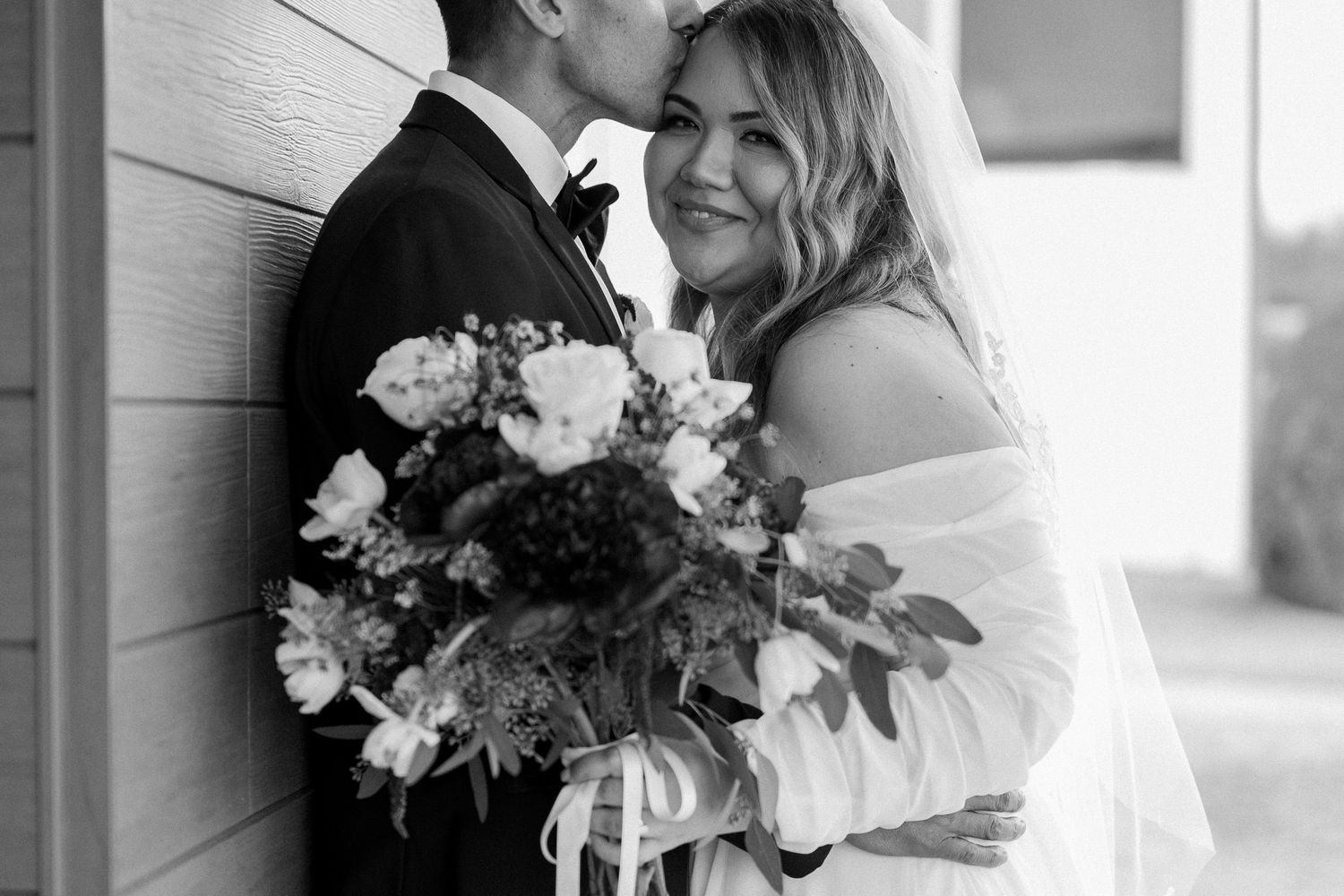 Close up black and white image of a bride cuddled with her groom at a winter wedding at a North Dallas, Texas venue