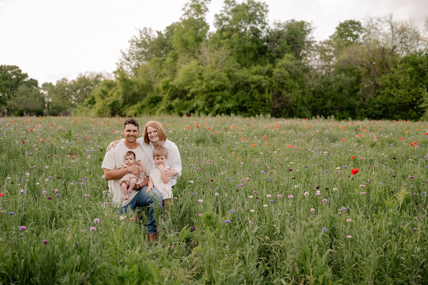 Family posing in large field of wildflowers on a clear day for a Spring family photo session in Richardson, TX